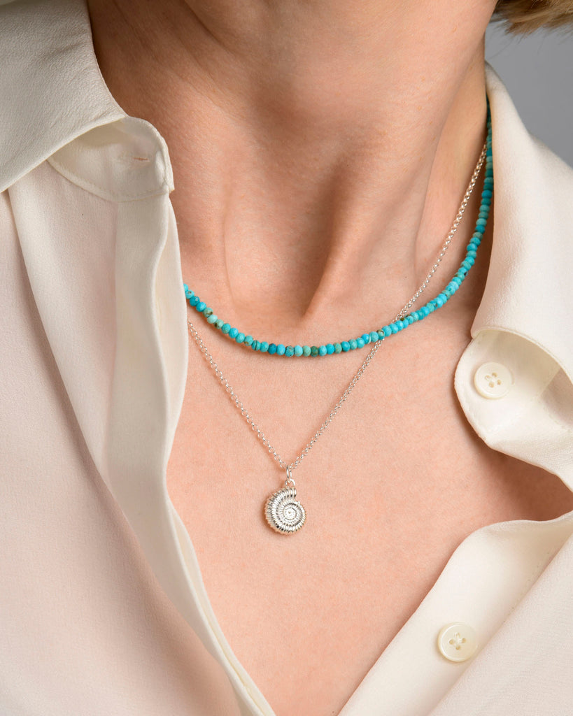 Woman wearing Turquoise bead necklace layered with a pendant necklace