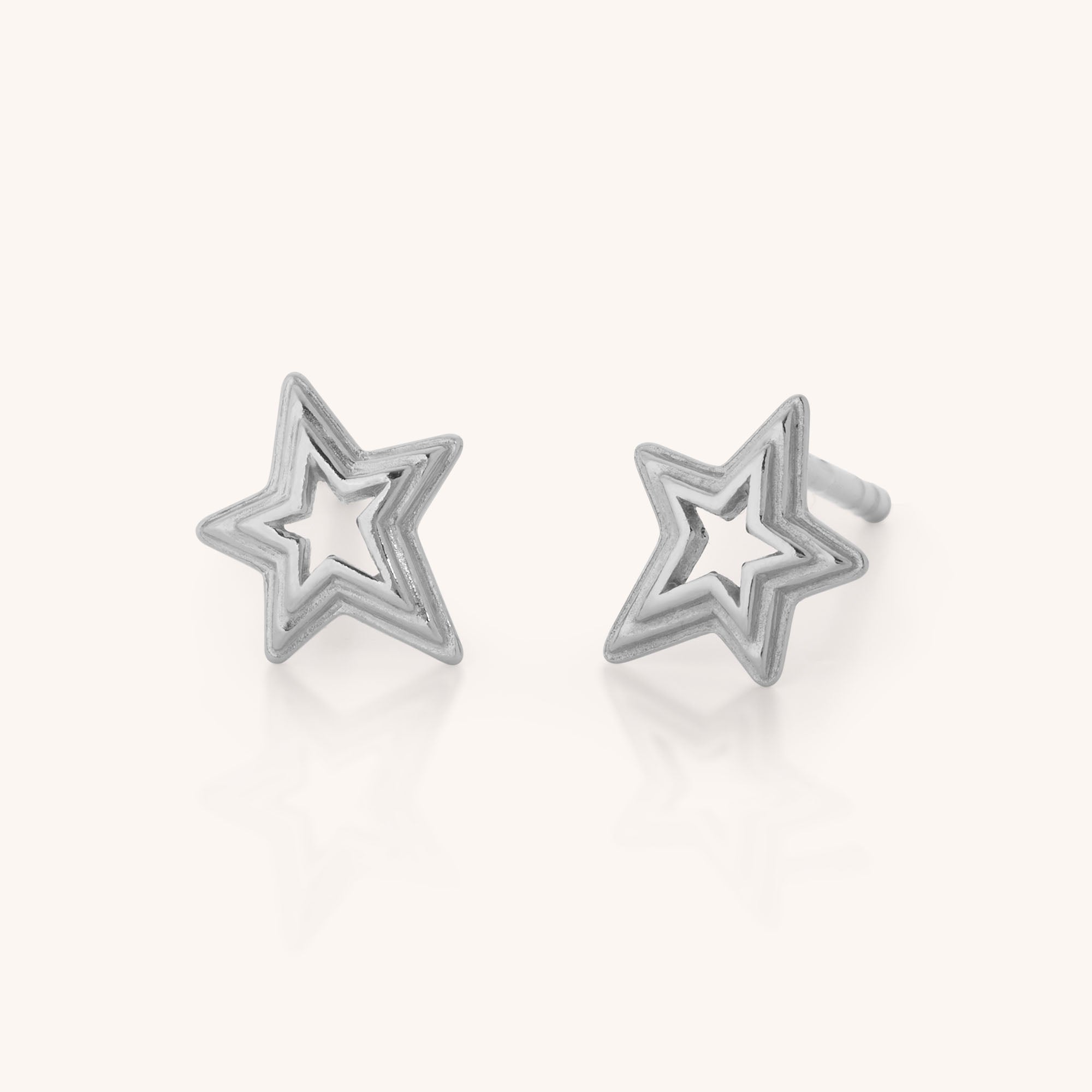 The Stellar Starburst Stud Earrings are sterling silver, star-shaped studs with open centers and a celestial design, shown on a light background.