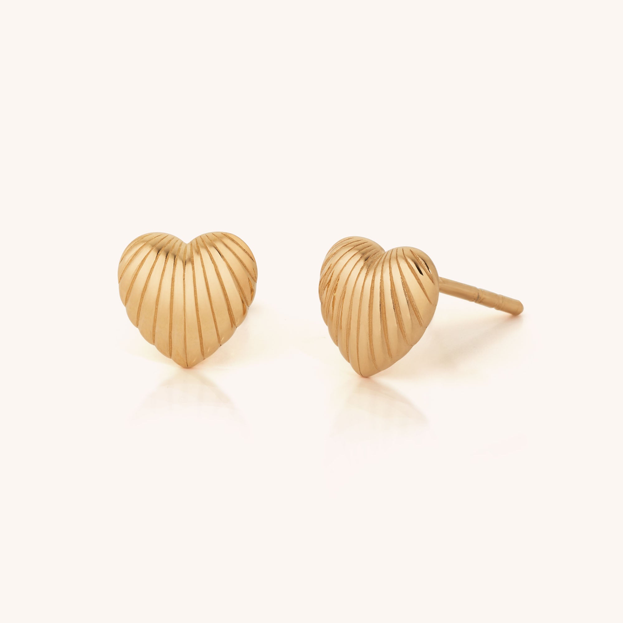 The Heart Beam Stud Earrings feature a gold, ridged, textured surface that radiates elegance and vibrancy—perfect for everyday wear and displayed on a plain light background.