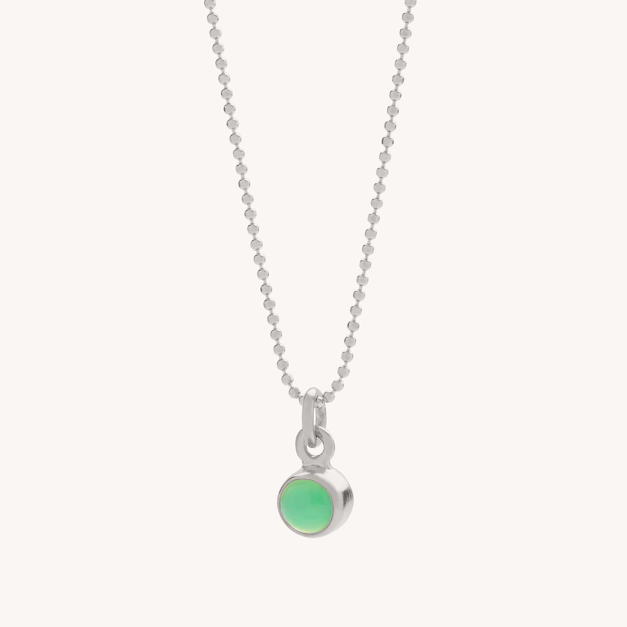 The Gem Dot Birthstone Necklace May features a silver beaded chain and a small, round natural Chrysoprase gemstone pendant in a simple silver setting, shown on a light background. This elegant necklace is loved for its healing properties.