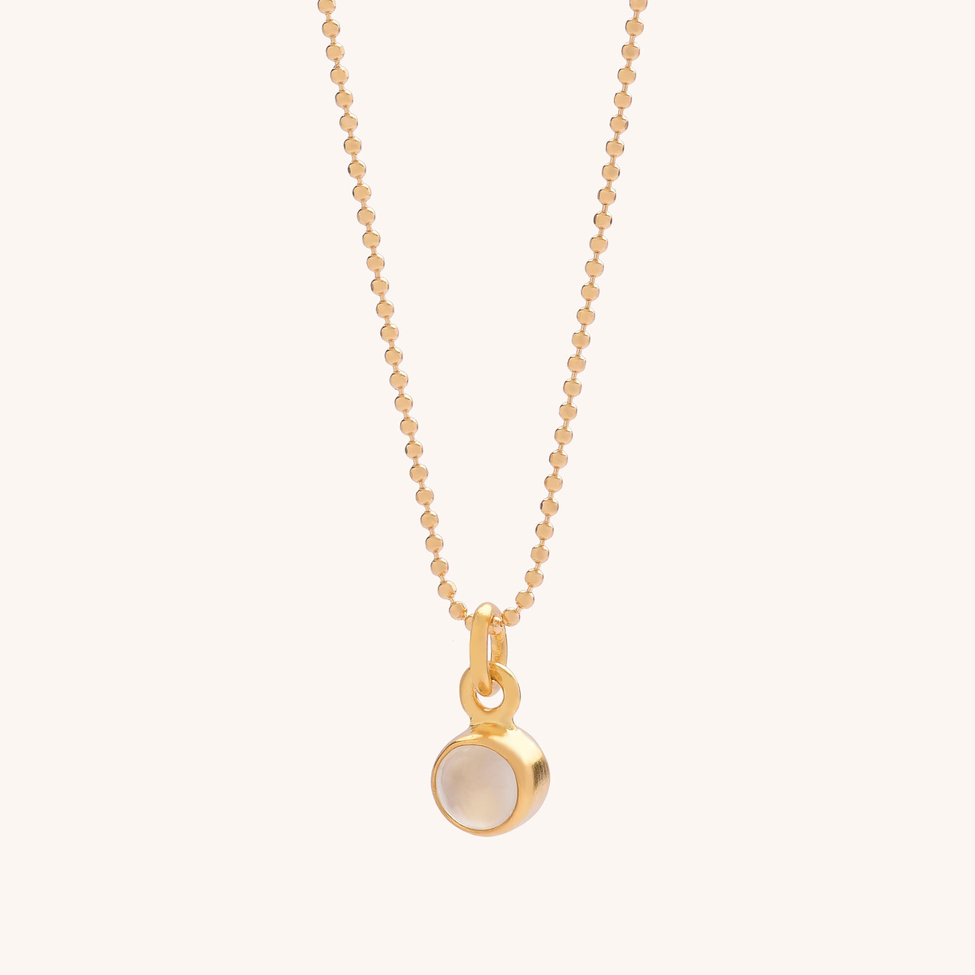 The Gem Dot Birthstone Necklace June features a gold beaded chain with a small, round, gold-framed moonstone pendant at the center—ideal for layering with other jewelry. Shown on a plain light background.