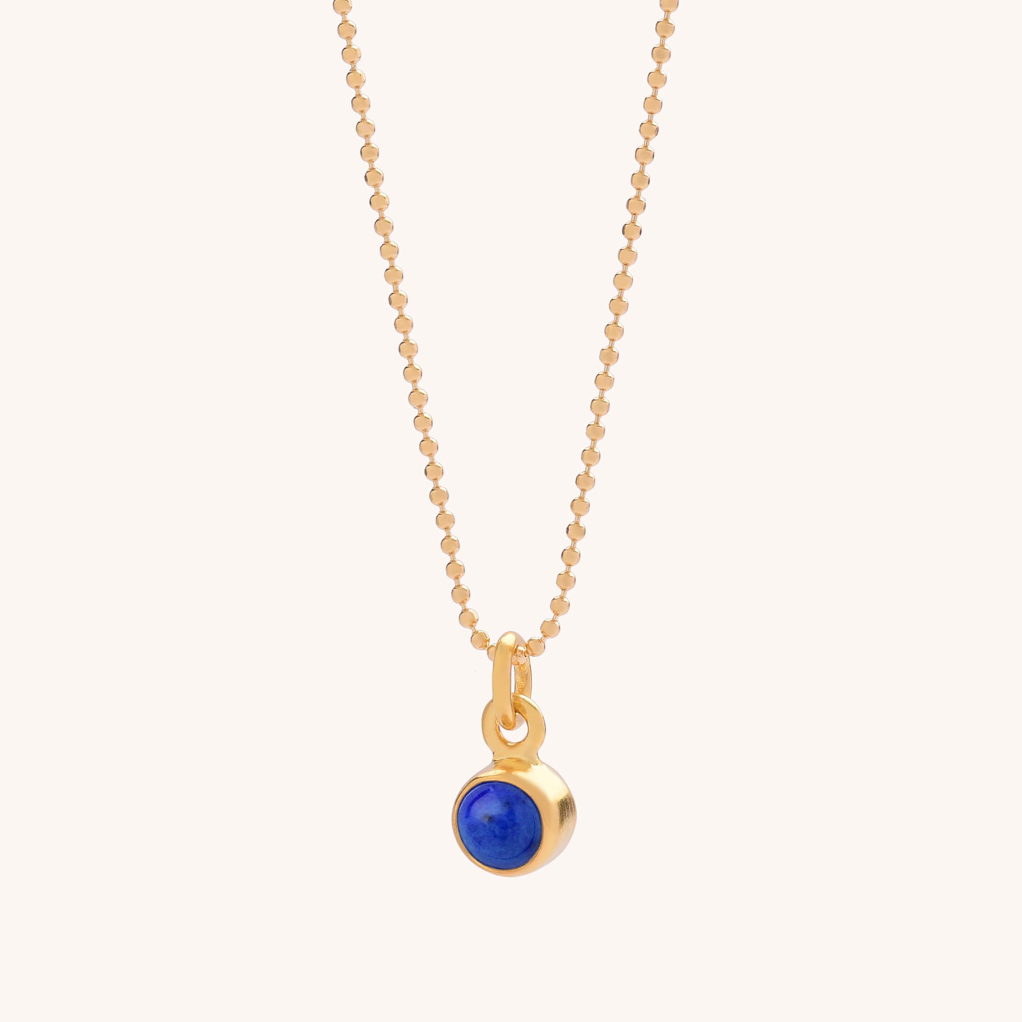 The Gem Dot Birthstone Necklace September features a delicate gold chain and a small round pendant with a deep blue Lapis gemstone bezel-set in gold—a beautiful tribute to the September birthstone.