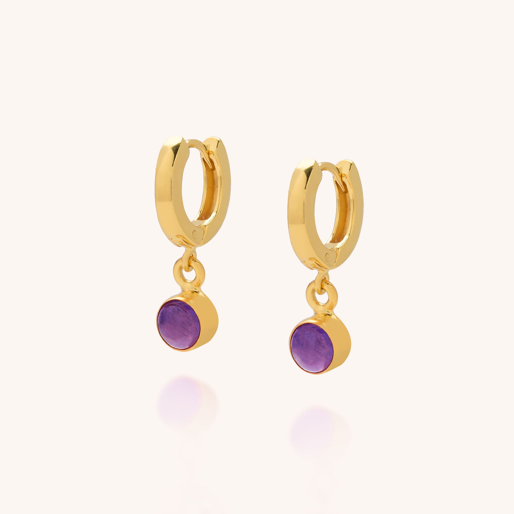 A pair of Gem Hoop Birthstone Earrings featuring small gold hoops with round natural gemstone charms, set against a light background.