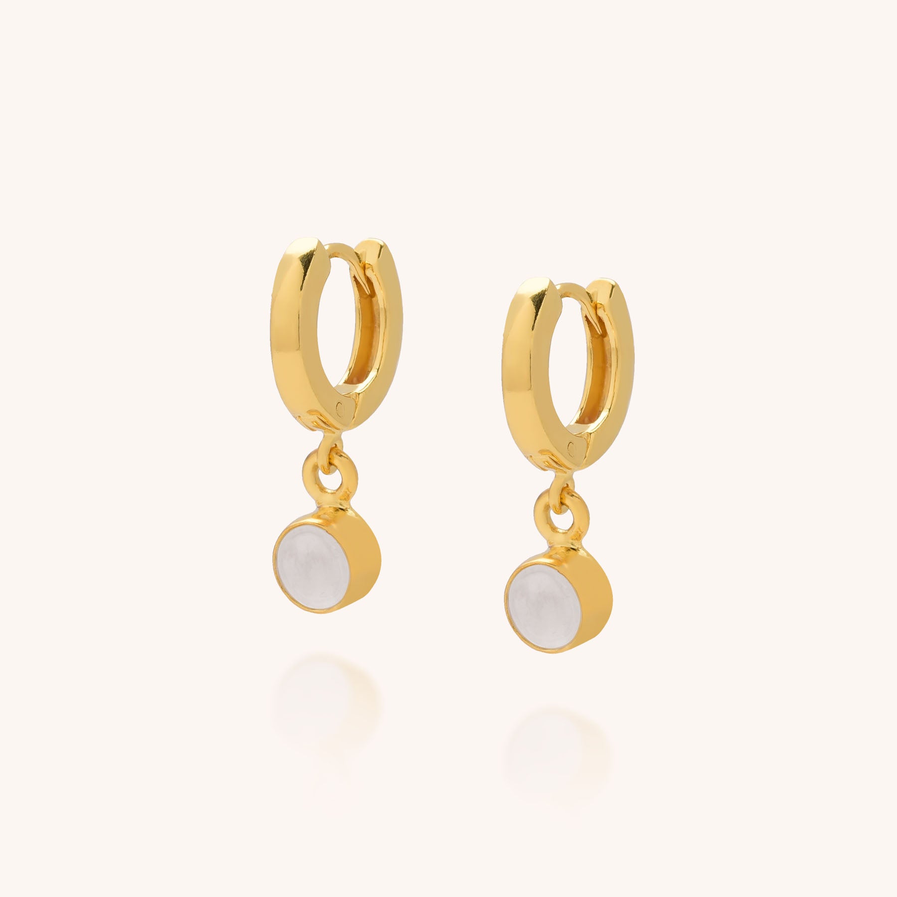 The Gem Hoop Birthstone Earrings are small gold hoops featuring round white natural gemstone pendants, shown on a plain light background.