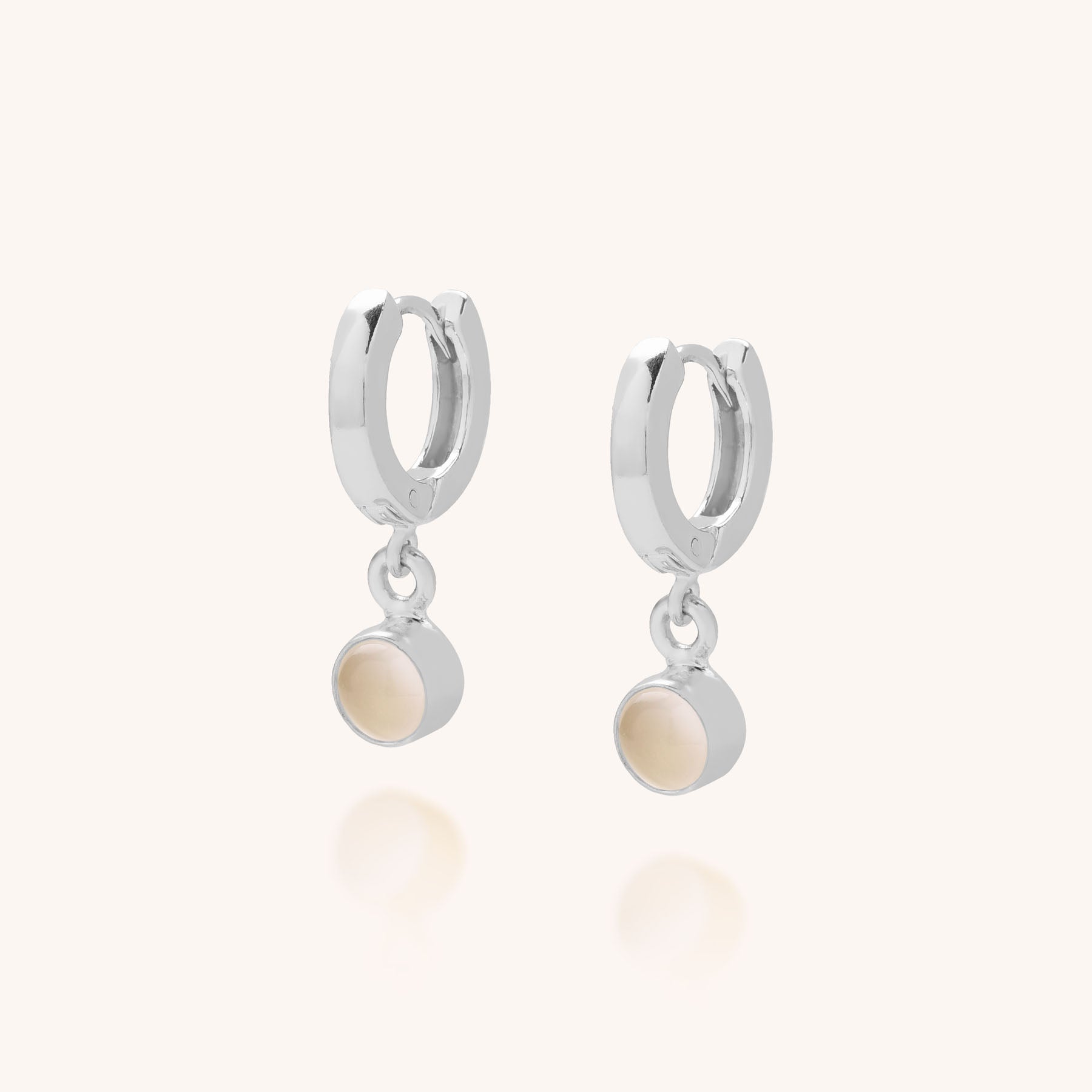 The Gem Hoop Birthstone Earrings are sterling silver hoops, each with a small round natural gemstone charm, displayed on a plain light background.