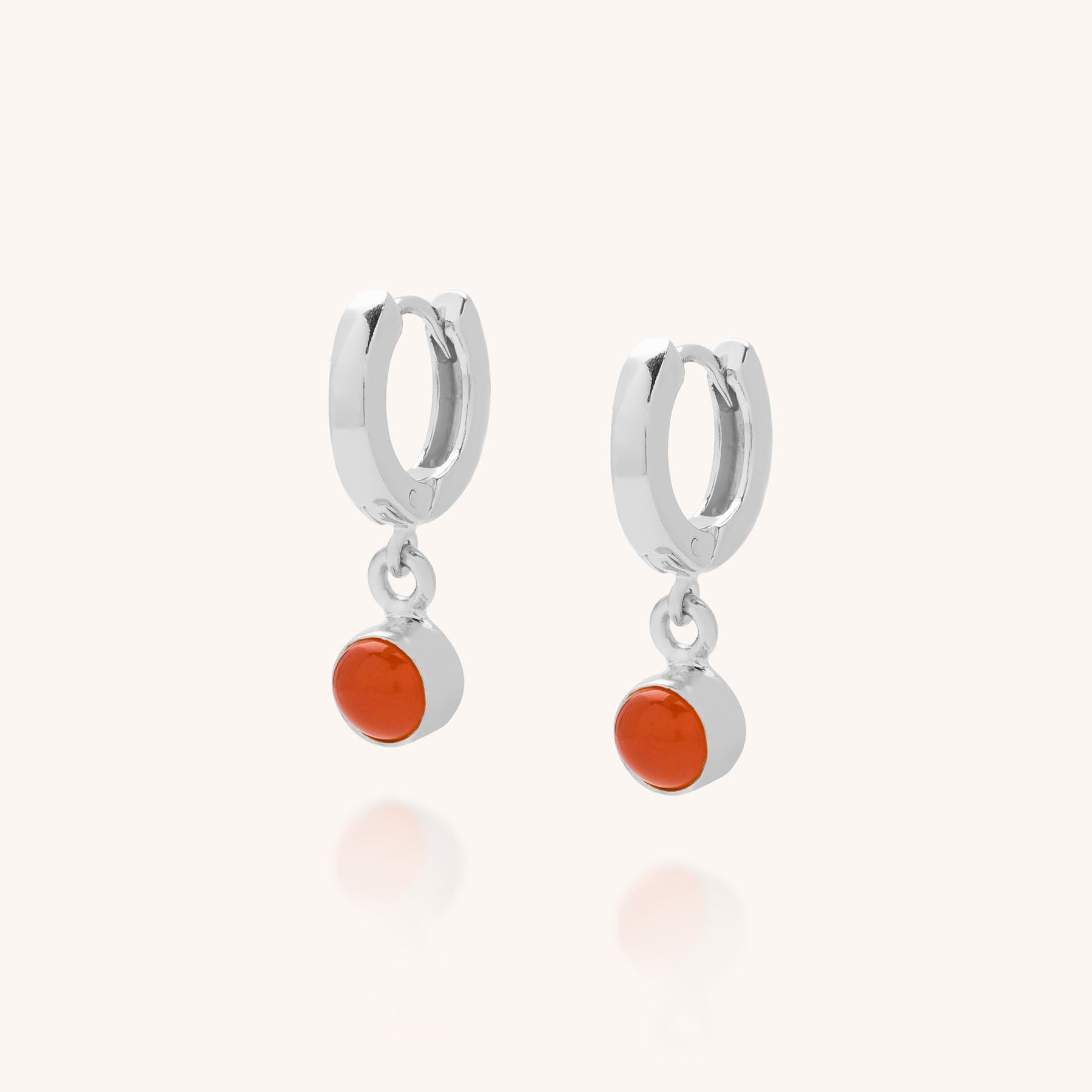 Gem Hoop Earrings - July Birthstone: Sterling silver ear hoops each feature a small, round carnelian dangle, shown against a light neutral background.