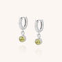 Gem Hoop Birthstone Earrings: Sterling silver hoops, each with a small round light green natural gemstone charm dangling below, shown on a plain light background.