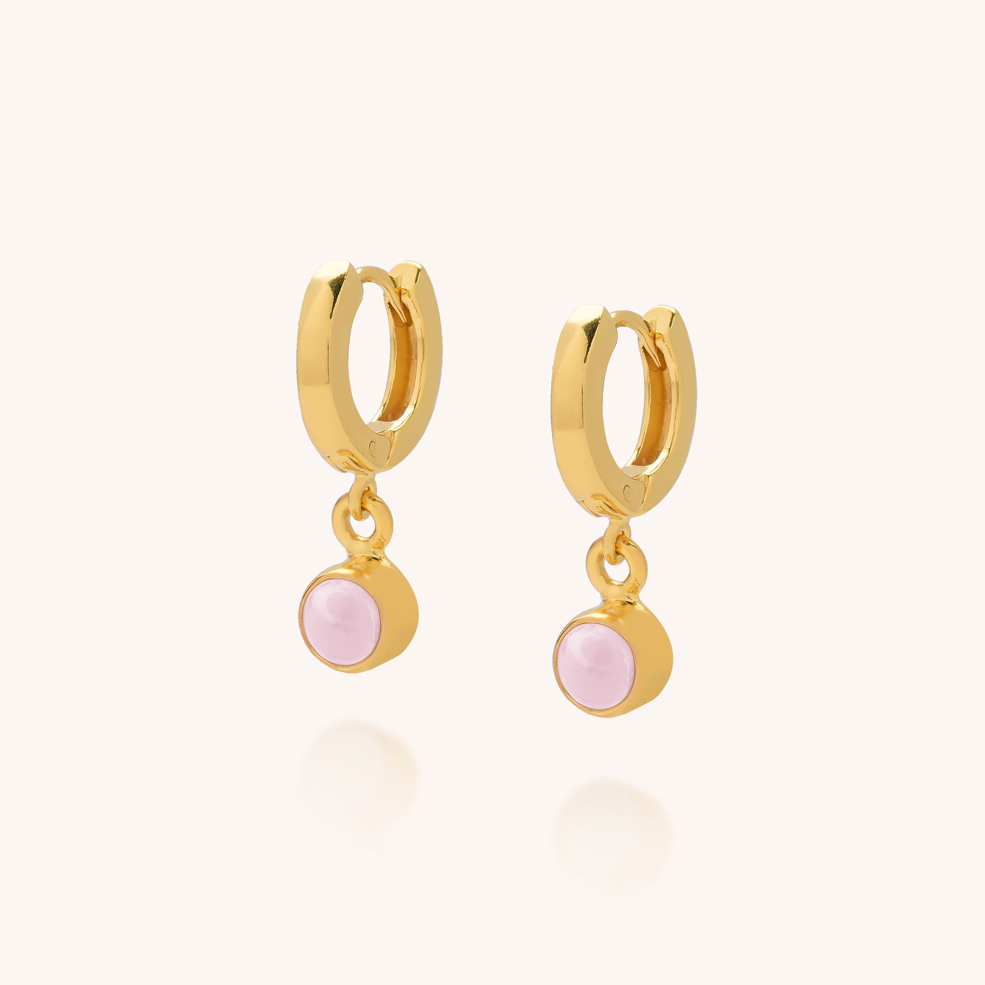 The Gem Hoop Earrings - October Birthstone feature gold hoops with small round Pink Opal charms, celebrated for emotional healing. Pink Opal is the birthstone for October. Set against a soft, neutral background.