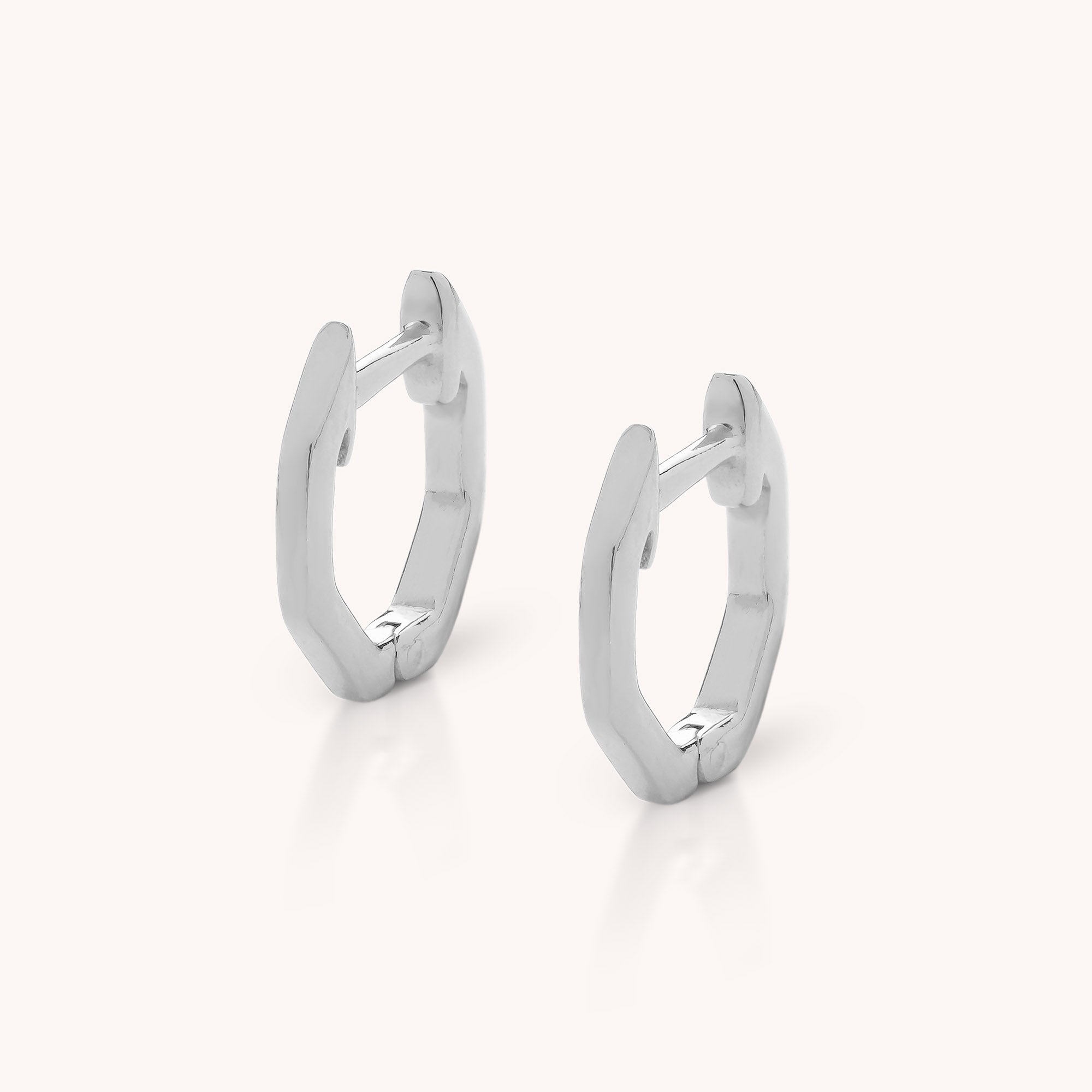 The Hex Huggie Earrings are sterling silver hoops with a geometric design and secure hinged clasp, displayed on a light background.