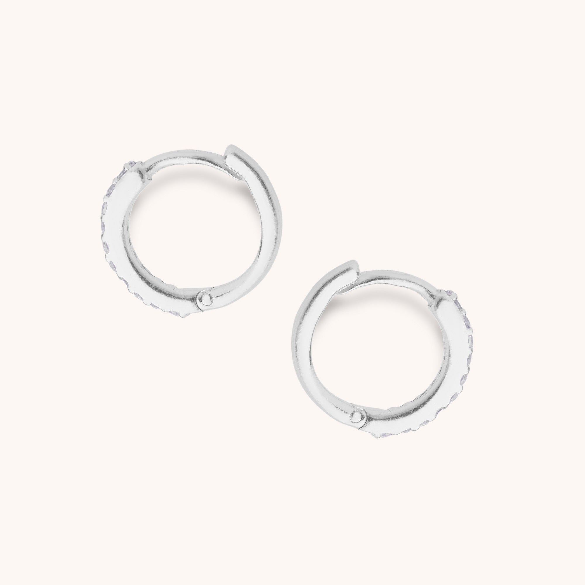 The Ava Huggie Earrings are small sterling silver hoops with a hinged closure, shown on a plain, light background.