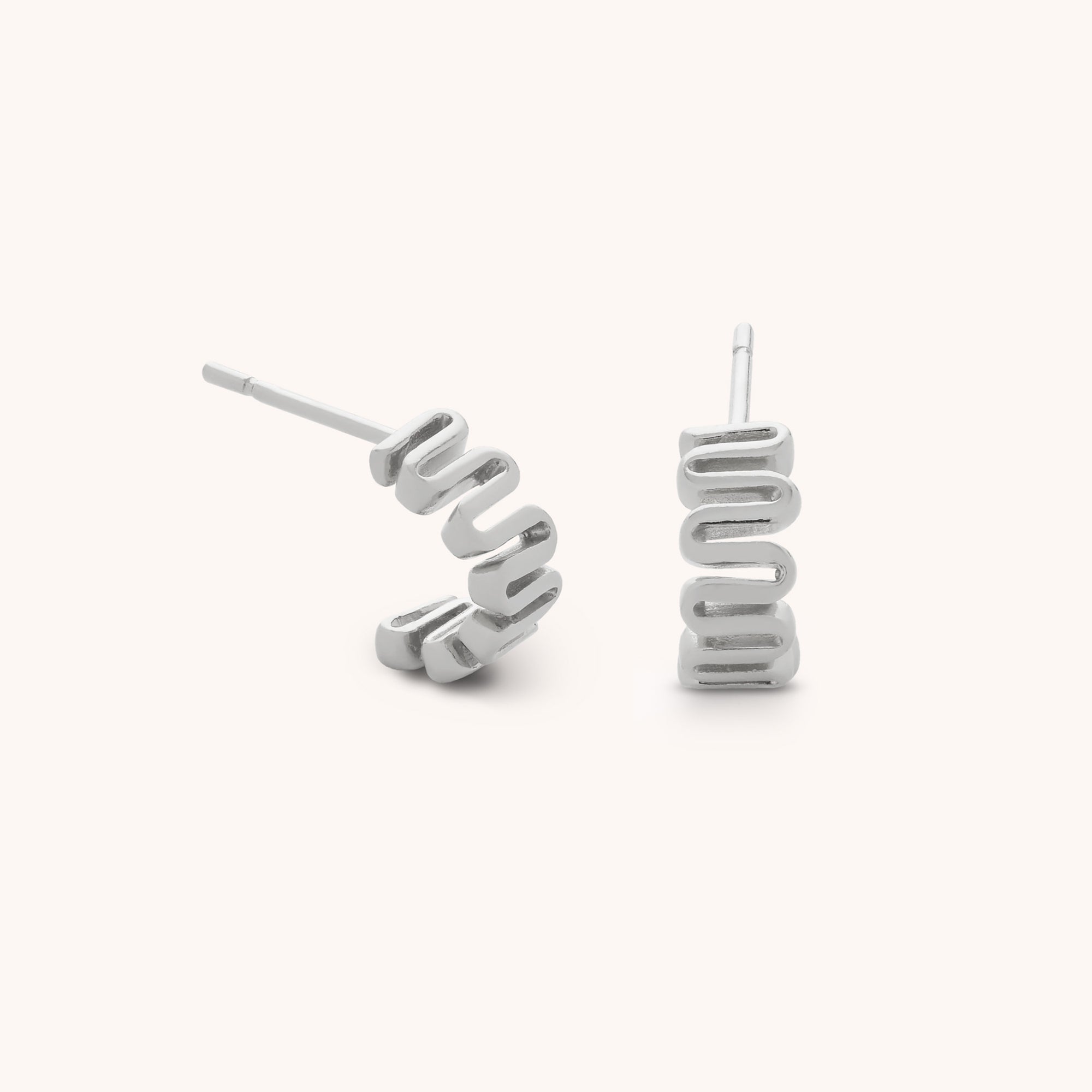 The Wiggle Hoop Earrings are sterling silver studs featuring a modern wavy zigzag design. Displayed on a plain light background, one earring lies flat while the other stands upright.