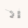 The Wiggle Hoop Earrings are sterling silver studs featuring a modern wavy zigzag design. Displayed on a plain light background, one earring lies flat while the other stands upright.