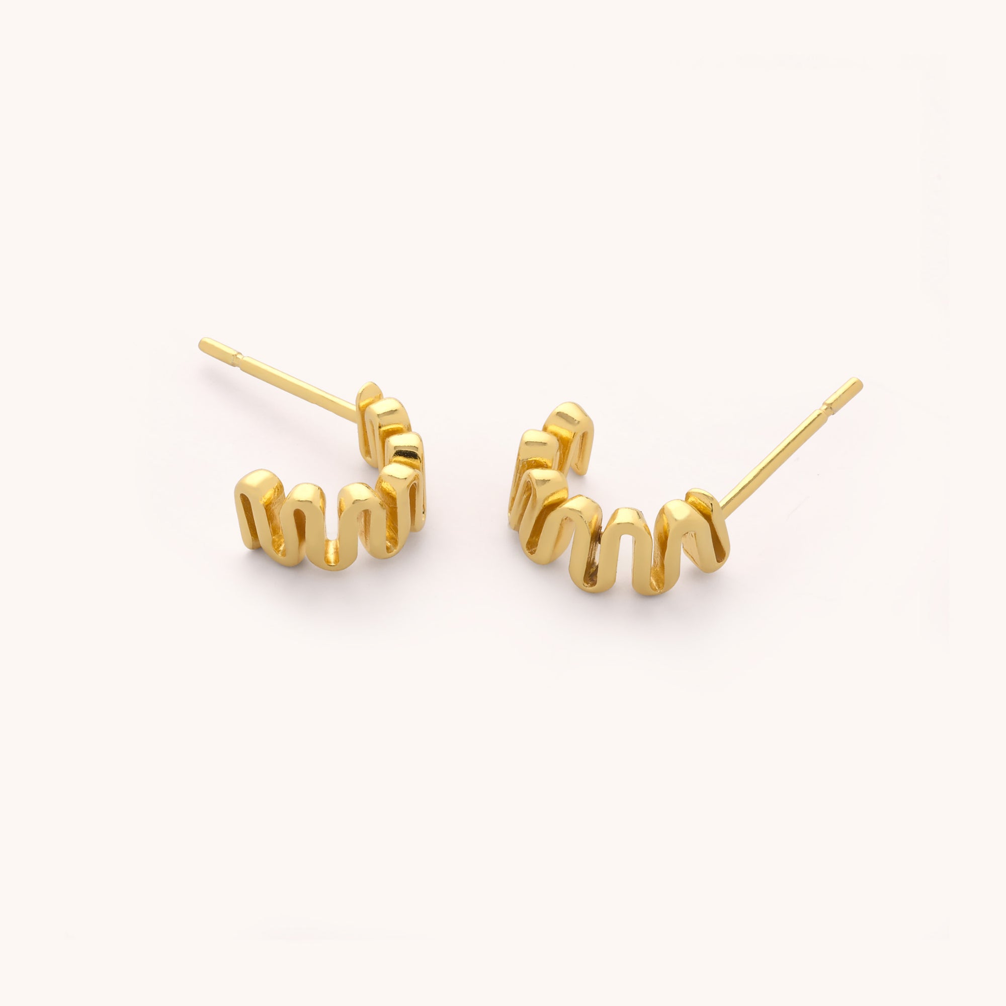The Wiggle Hoop Earrings feature a wavy, zigzag design in 18ct gold plating and include straight posts for pierced ears, shown against a plain white background.