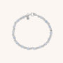The Gem Bracelet March Birthstone features alternating small silver and aquamarine beads, a silver clasp, and a round charm engraved with the letter N. This birthstone bracelet is shown against a light background.