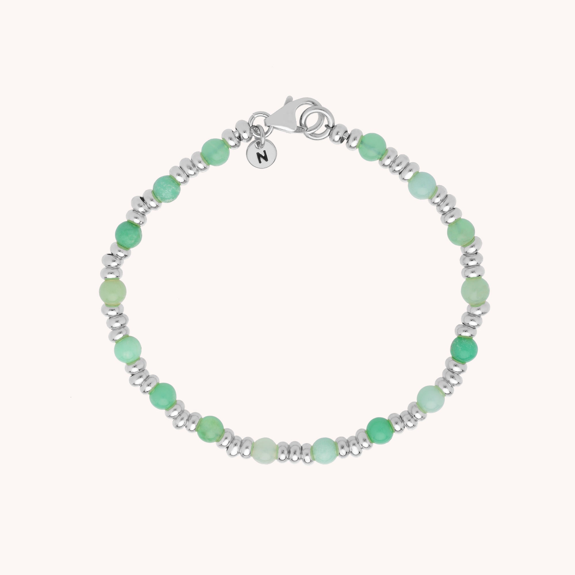 Introducing the Gem Bracelet May Birthstone: a delicate bracelet with alternating light green chrysoprase beads and silver spacers, finished with a lobster clasp and a round charm engraved with N.