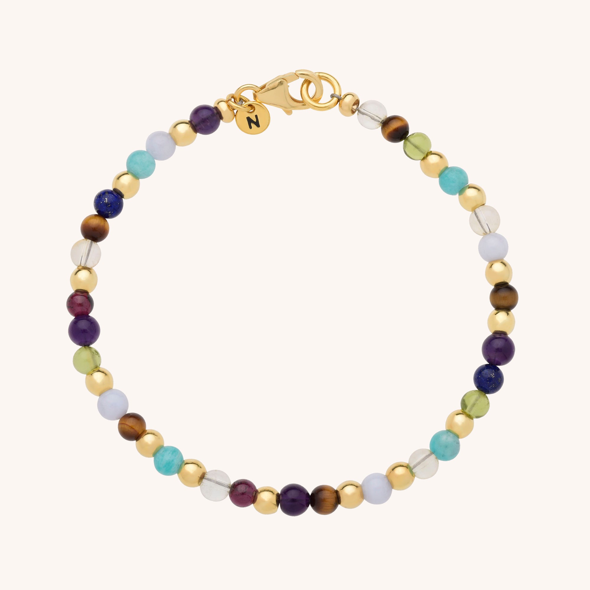 The Multi Gemstone Bracelet features alternating round beads in gold, purple, blue, turquoise, white, and clear tones, finished with a gold clasp and a small round charm.