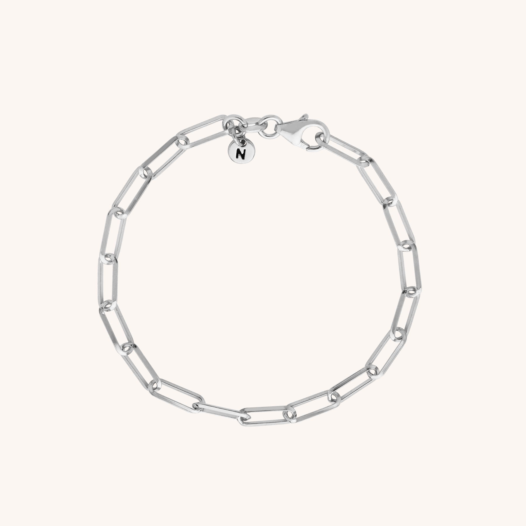 The Triangular Paperclip Bracelet features eco silver elongated oval links and a round charm engraved with N, beautifully displayed on a plain light background.
