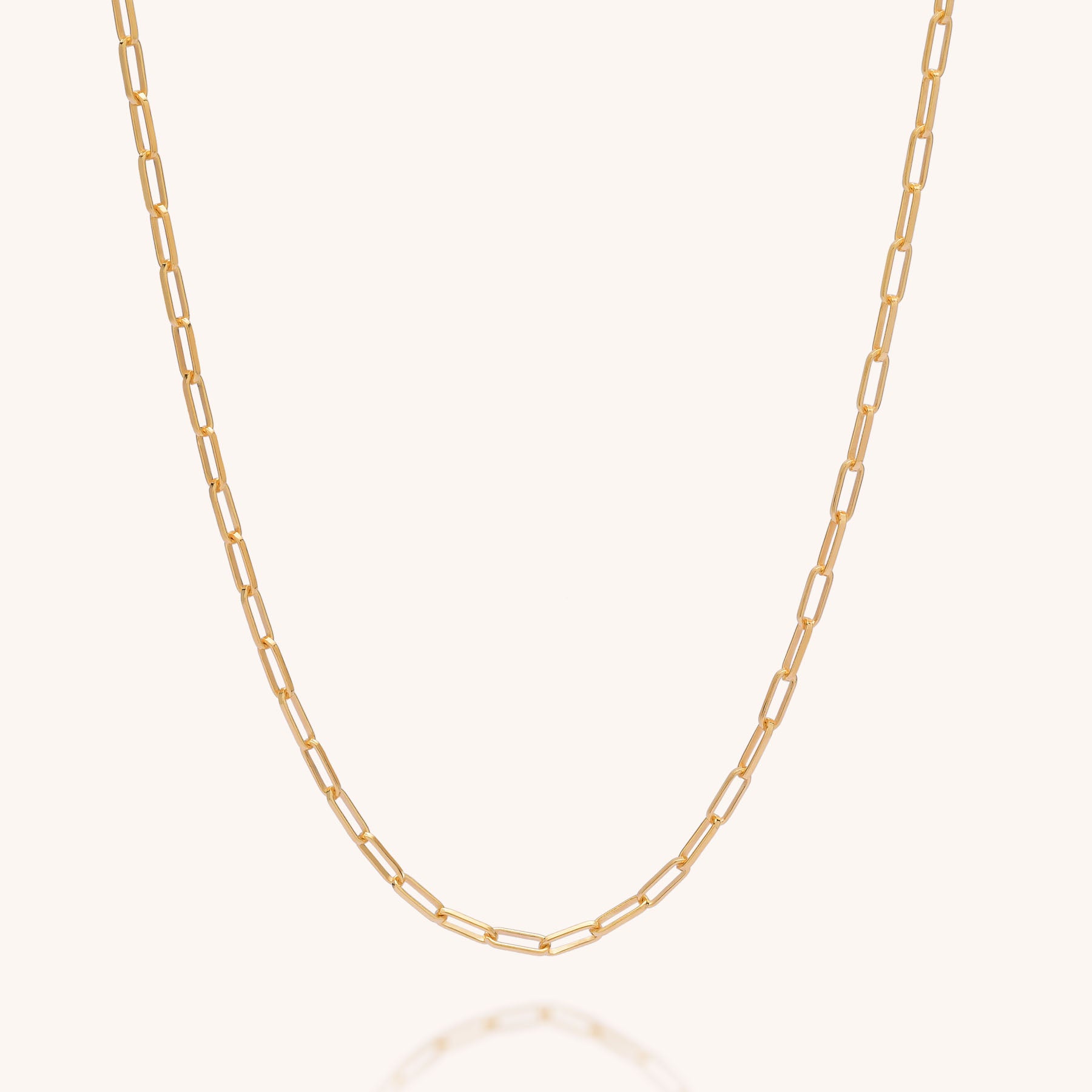 The Baby Paperclip Chain Necklace features delicate, elongated gold links and is displayed on a simple, light background—a timeless, sustainable accessory perfect for everyday elegance.