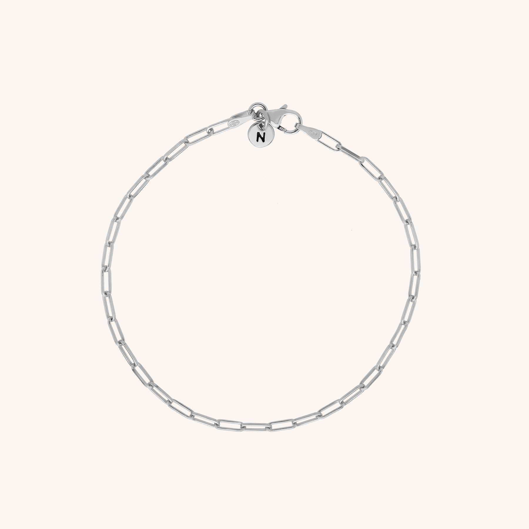 The Baby Paperclip Bracelet is a delicate eco-silver chain with elongated links and a round charm engraved with the letter N, shown on a plain light background.