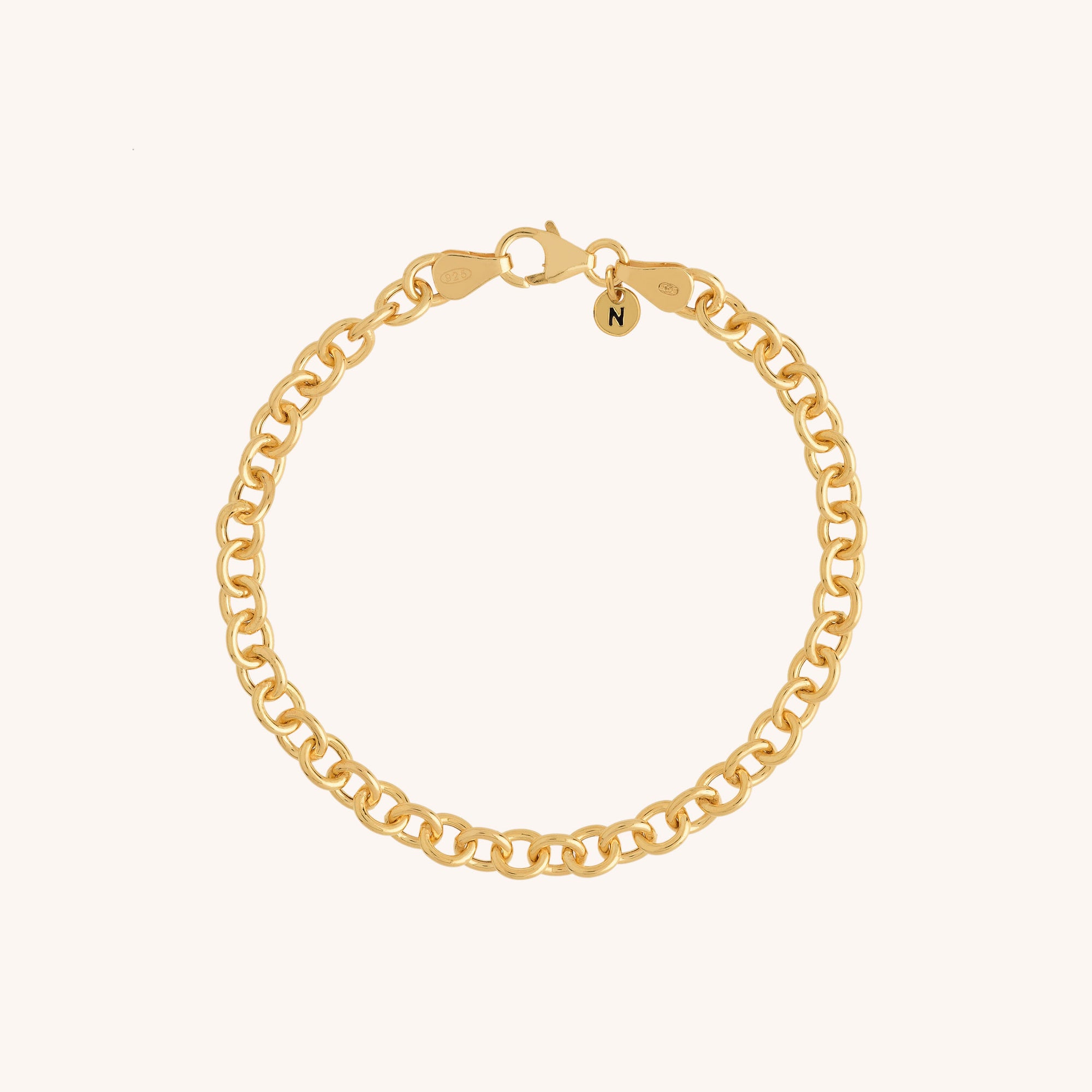 The Chunky Belcher Bracelet is gold plated with medium-sized links, a lobster clasp, and a small round charm engraved with the letter N, shown on a light beige background.