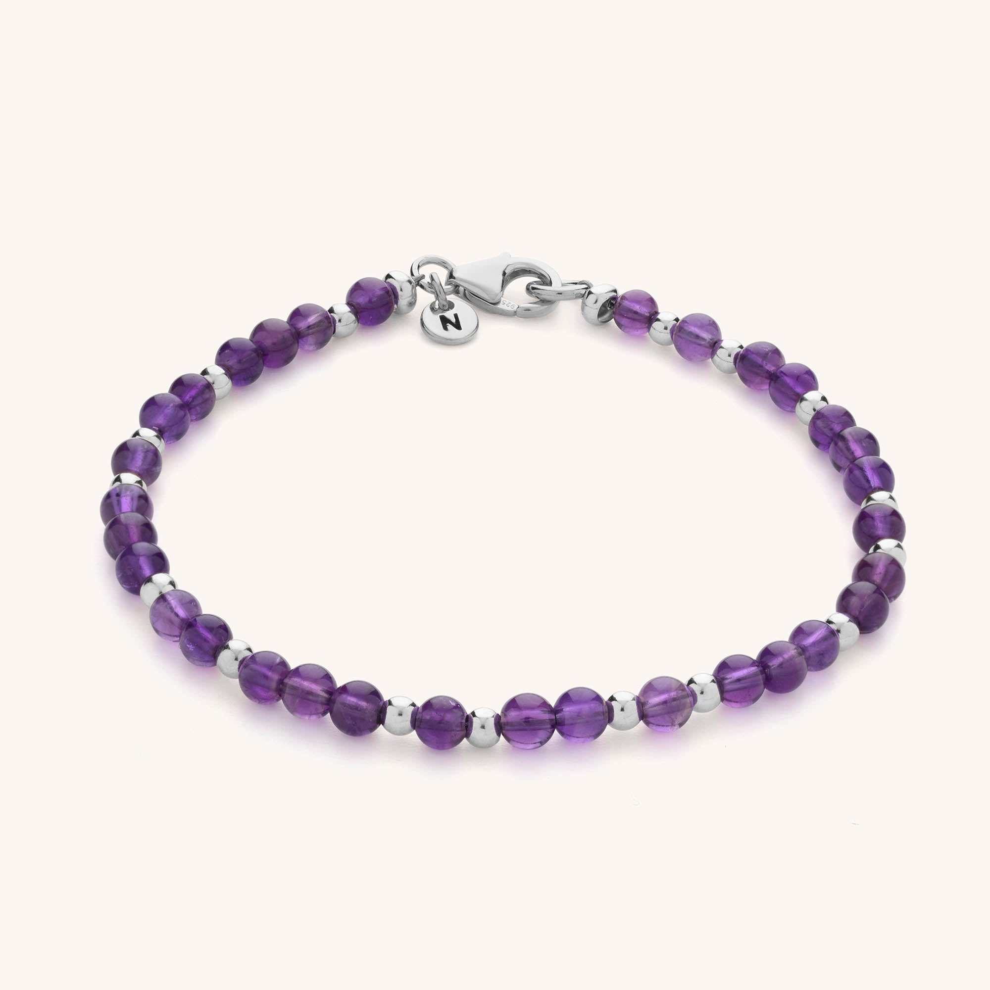 The Jewel Bead Birthstone Bracelet features round purple beads with silver spacers, a lobster clasp, and a small round charm—ideal as handmade jewellery or a thoughtful birthstone bracelet gift.