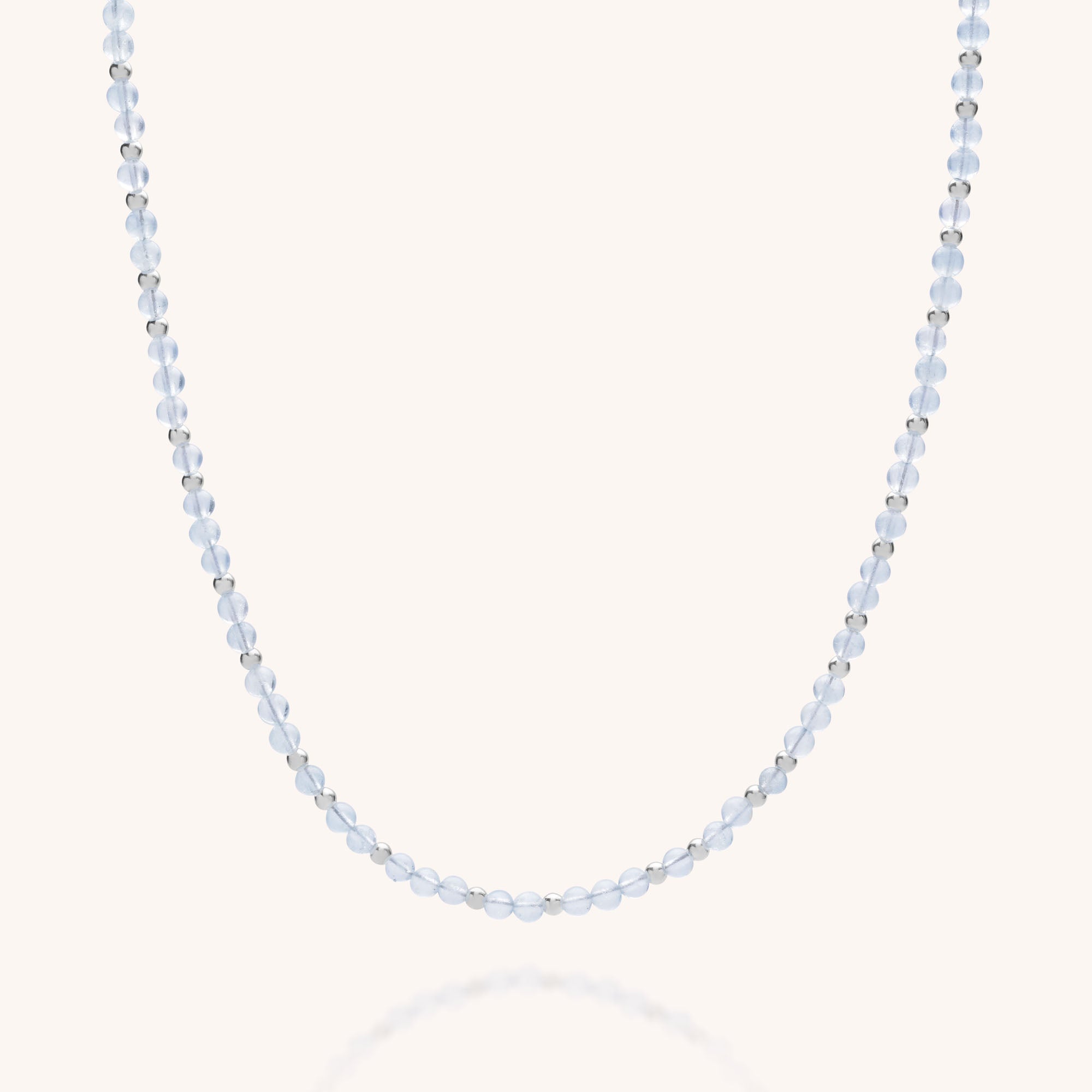 The Jewel Bead Birthstone Necklace - March features alternating translucent light blue beads and small silver beads, displayed on a light background—a beautiful piece of eco-friendly jewelry.