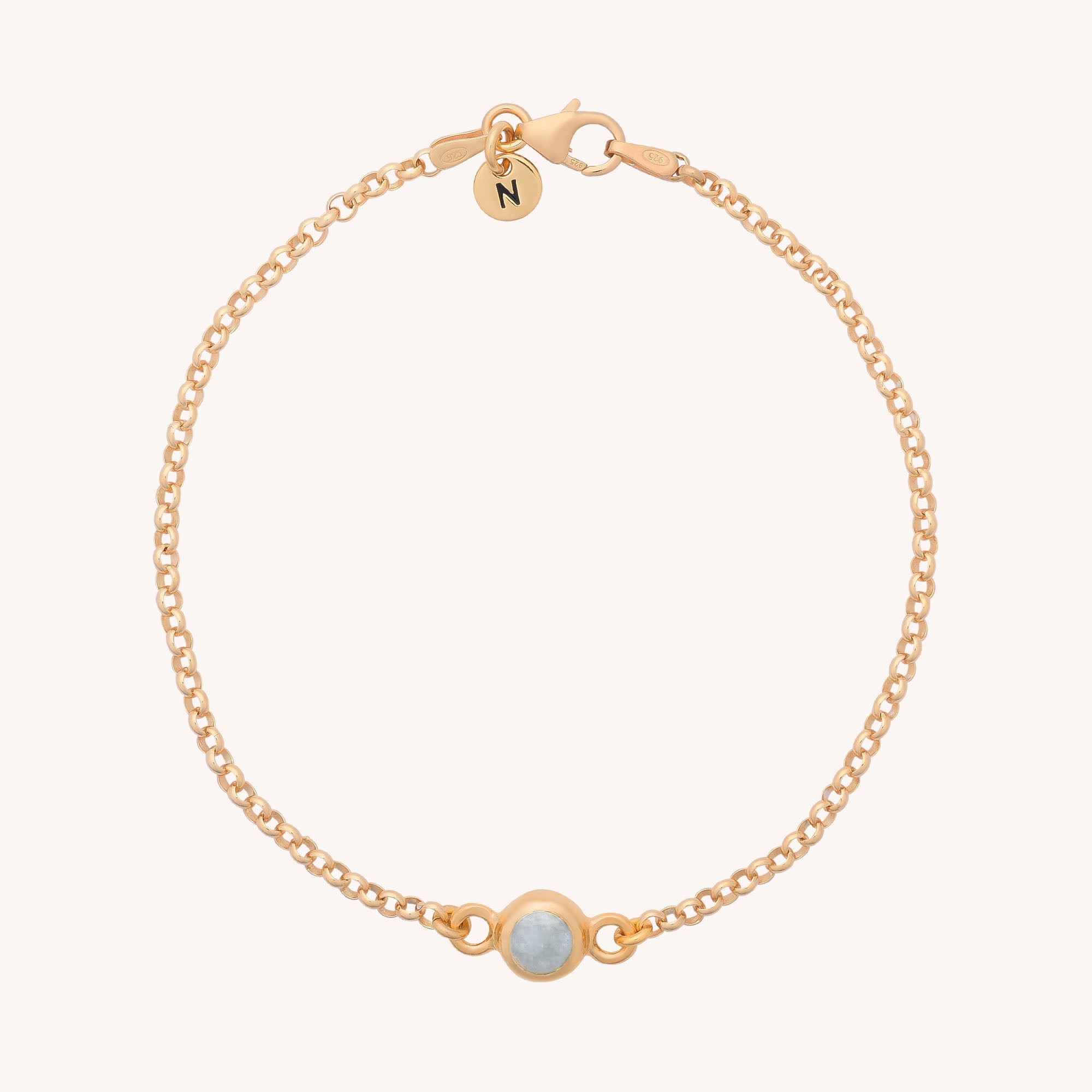 The Birthstone Gem Dot Bracelet features a delicate gold chain with a round white gemstone centerpiece and a small circular charm near the clasp, shown against a light background.