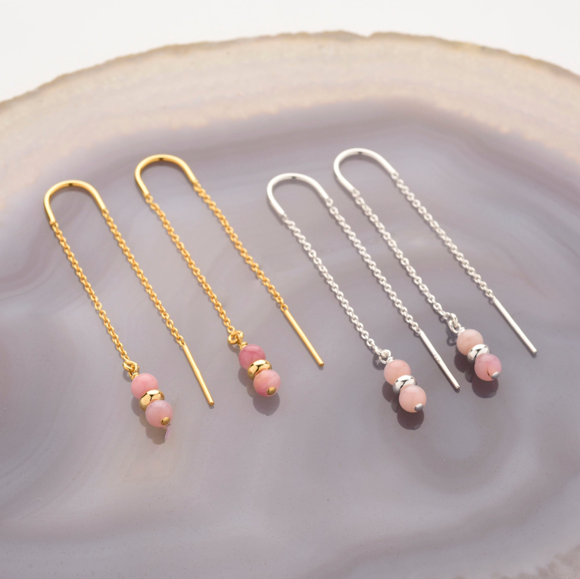 Two pairs of Fall Earrings Birthstone October threaders, one in gold and one in sterling silver, rest on agate—each pair features three Pink Opal beads delicately near the ends.