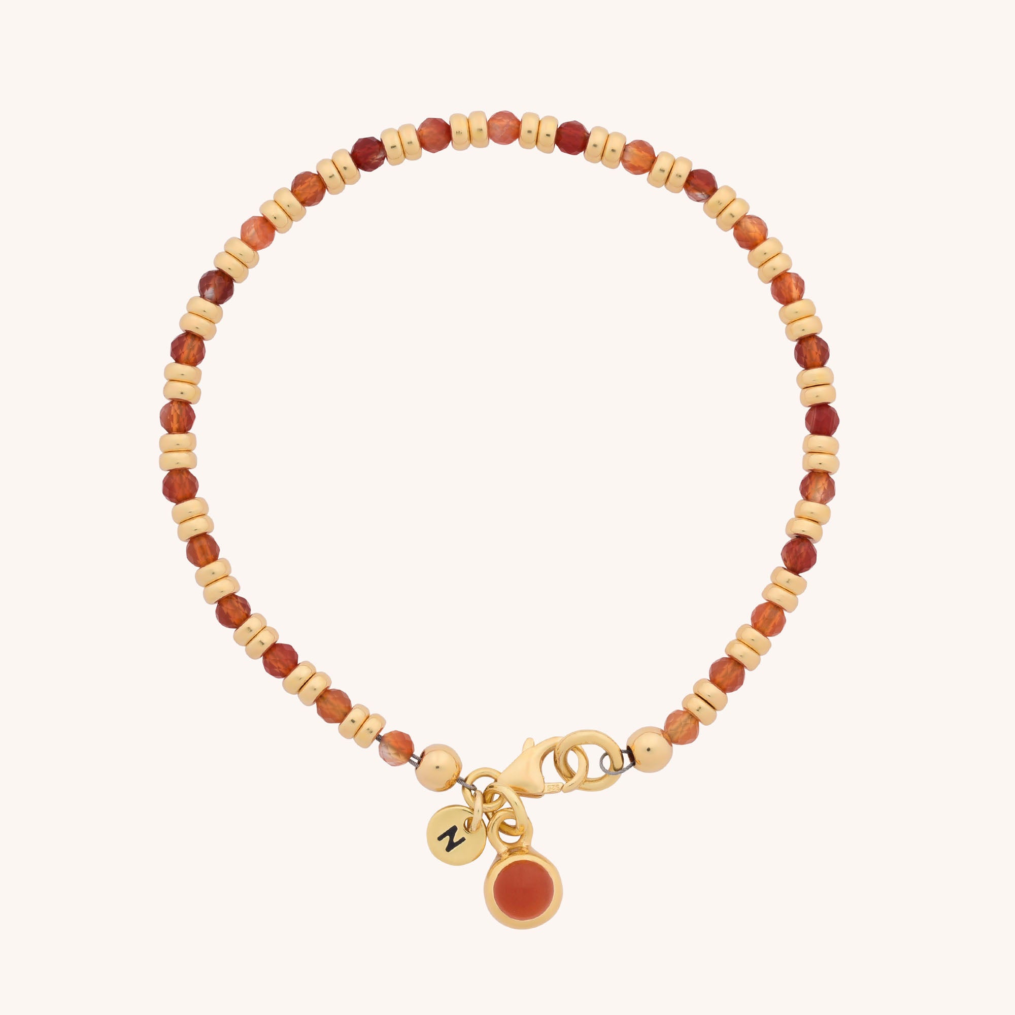 The Linear Birthstone Bracelet - July is a beaded Carnelian bracelet with alternating light and dark brown beads, gold clasp, and two small gold charms—one set with an orange gem, one engraved with ZV.