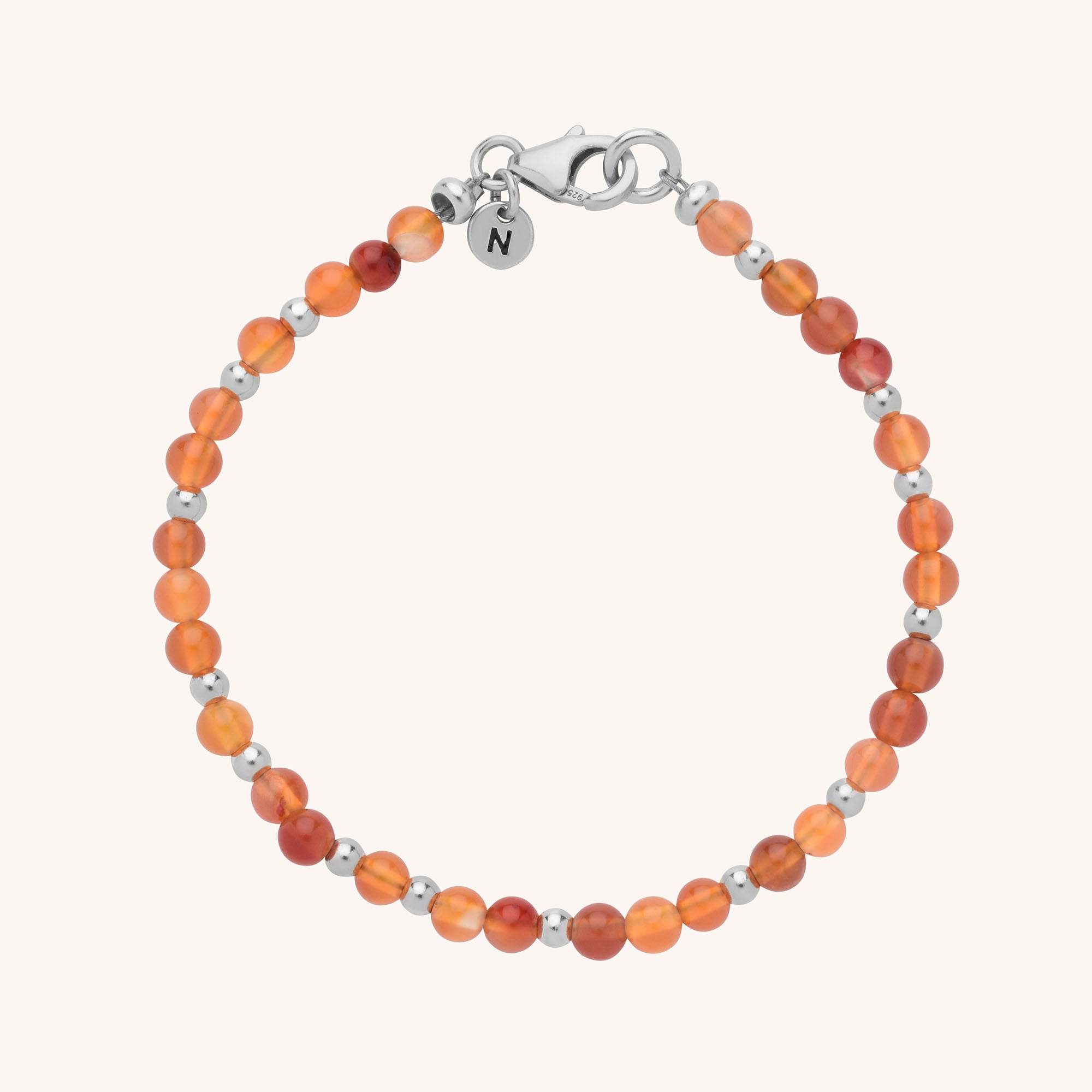 The Jewel Bead Birthstone Bracelet - July features small round carnelian stones and eco-friendly sterling silver beads, finished with a silver lobster clasp and a round tag engraved with the letter N.