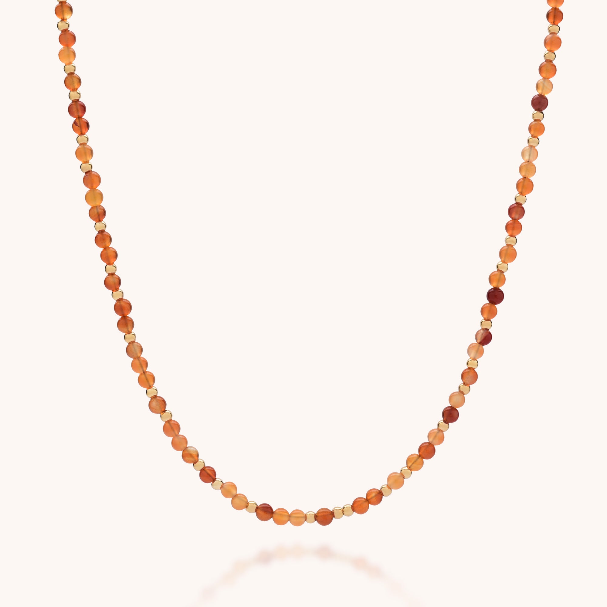 The Jewel Bead Birthstone Necklace - July features alternating small round Carnelian beads in orange, amber, and gold for a simple, elegant look. Carnelian is the birthstone for July.