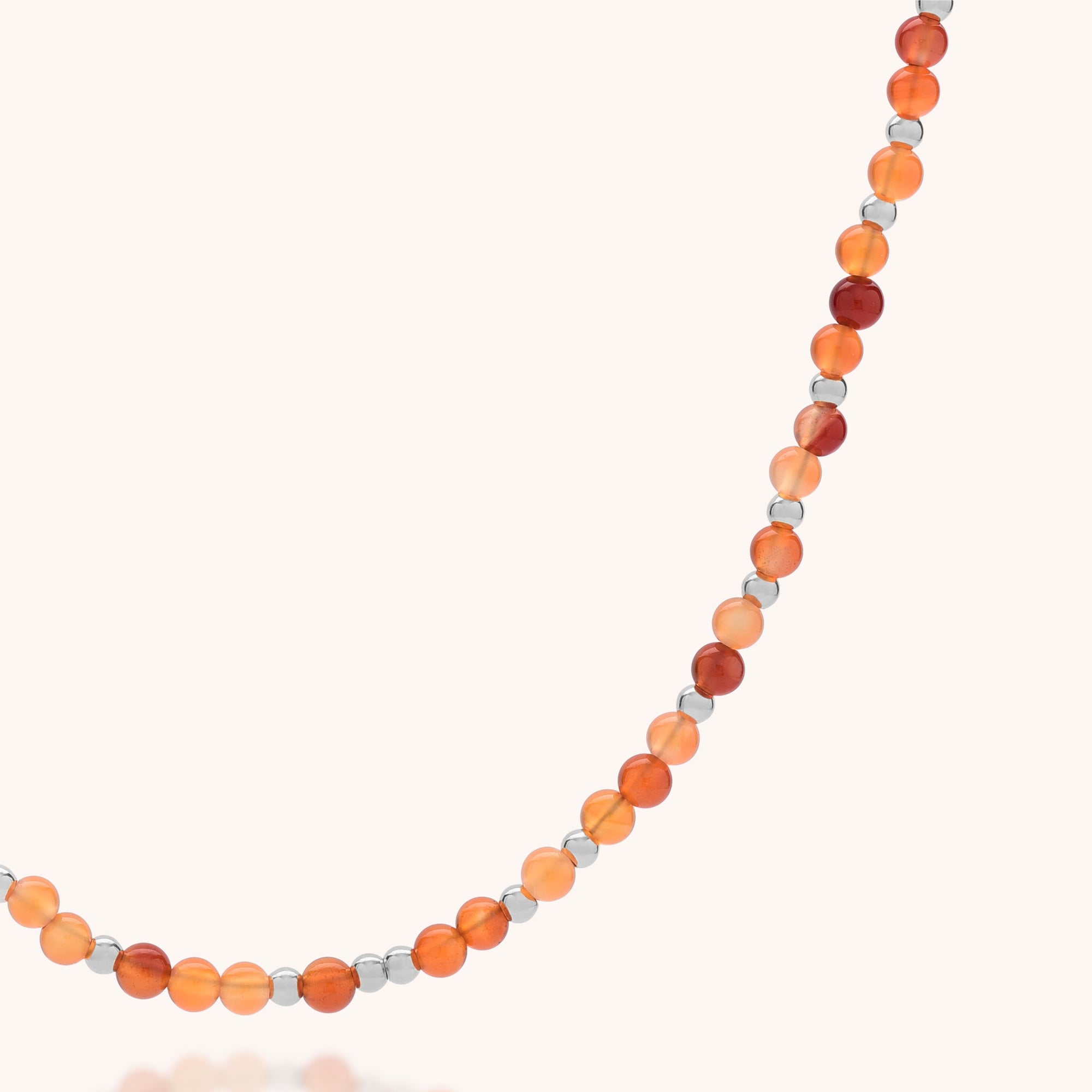 The Jewel Bead Birthstone Necklace - July features alternating round orange and red carnelian beads with eco-friendly sterling silver spacers, beautifully displayed on a light background.