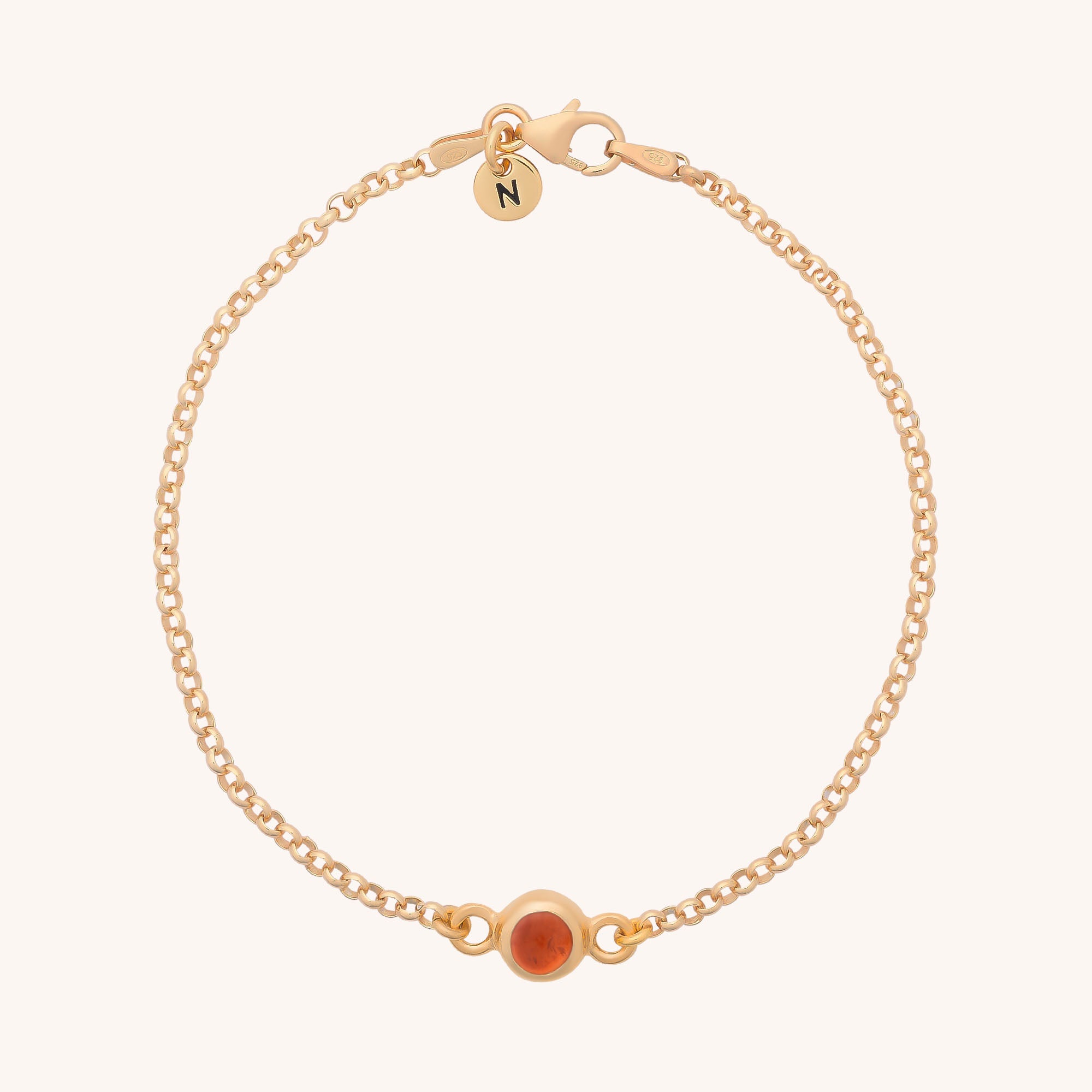 The Birthstone Gem Dot Bracelet - July features a gold chain with a small round carnelian and a circular charm with the letter N near the clasp, displayed on a light background.