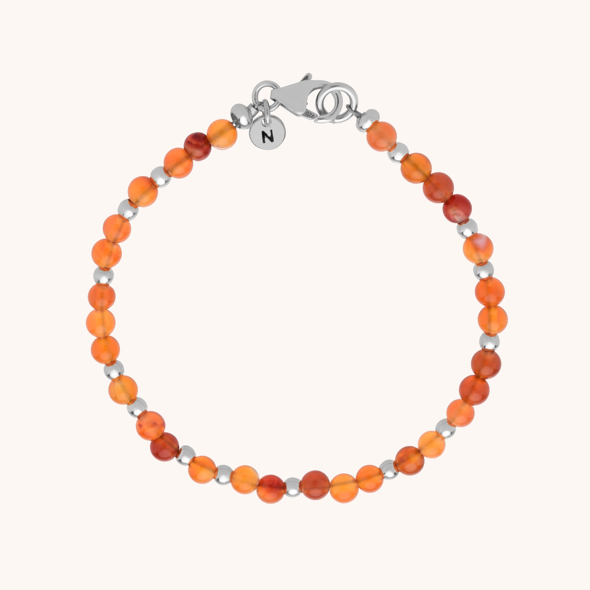 The Jewel Bead Bracelet showcases round orange and red translucent natural gemstones with small eco-silver sterling silver beads, finished with a silver lobster clasp and an N engraved charm.