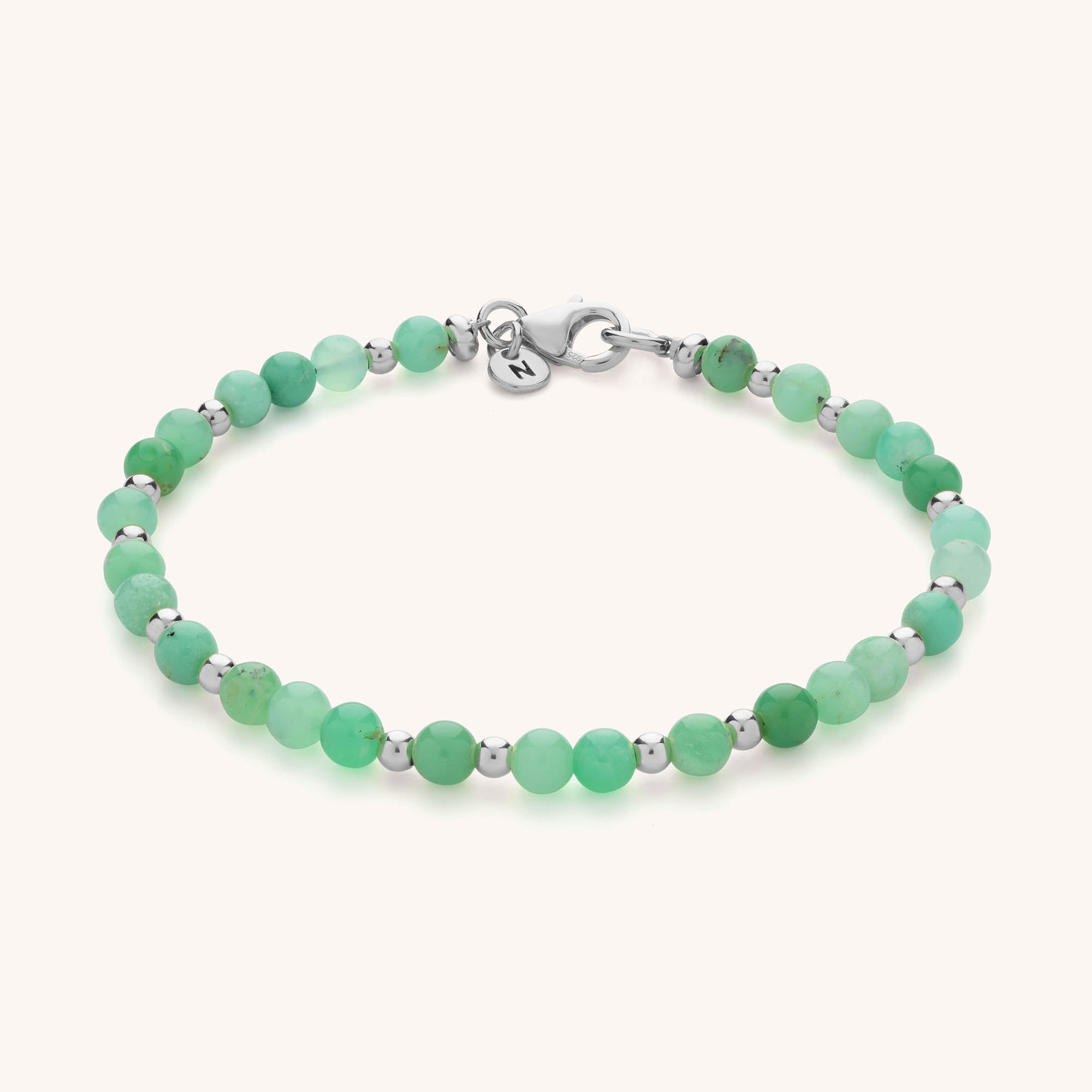 The Jewel Bead Birthstone Bracelet features small round green beads, silver spacers, a silver clasp, and a round charm—an ideal handmade jewellery gift for anyone who loves personalized style.