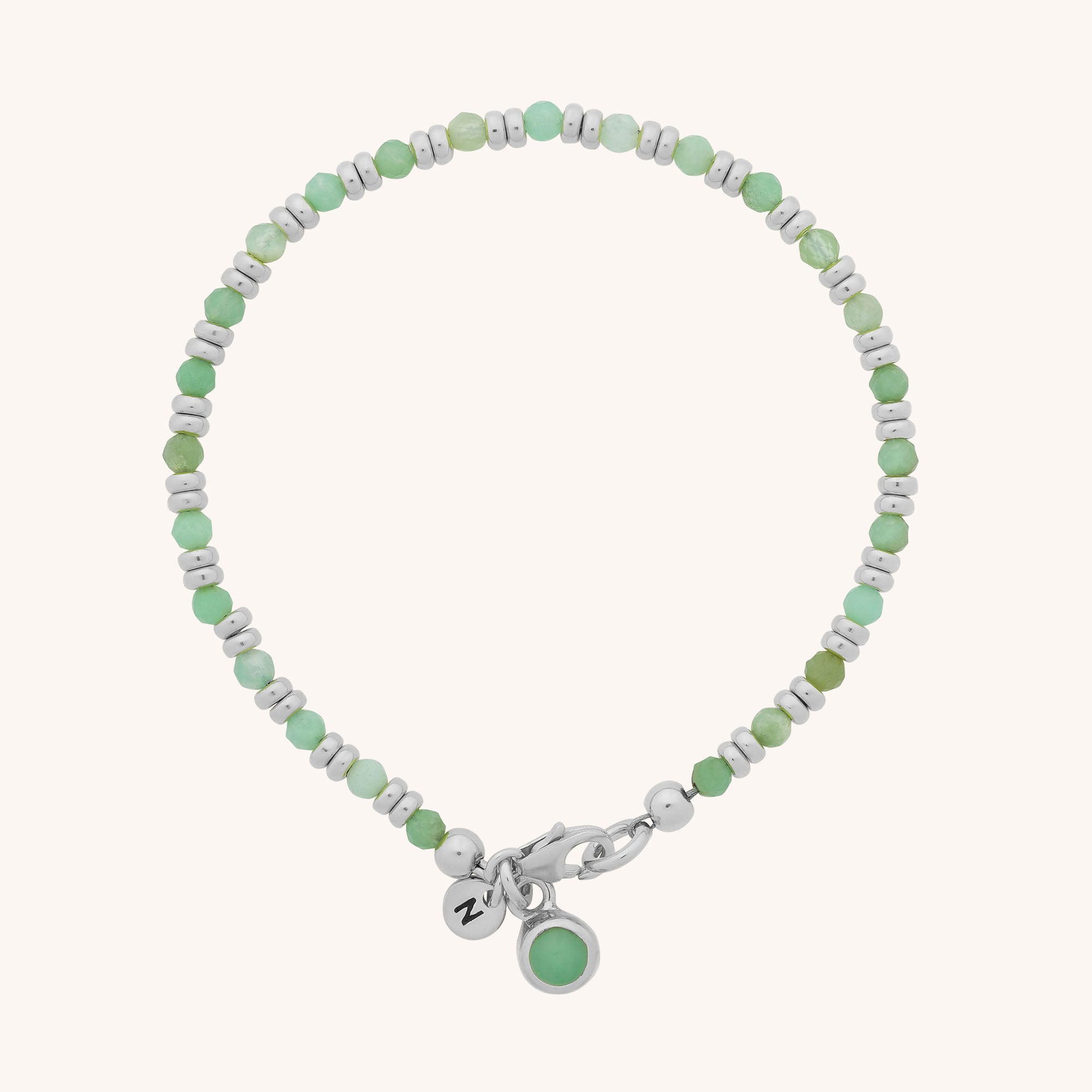 The Linear Birthstone Bracelet - May features alternating green Chrysoprase and silver beads, a silver clasp, a round green charm, and a silver tag engraved with N—a perfect gift for May birthdays.