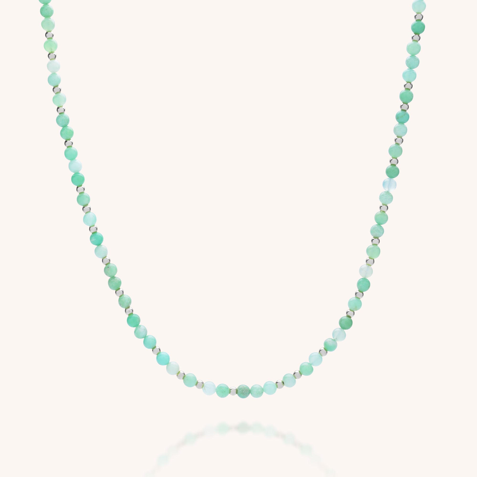 The Jewel Bead Birthstone Necklace - May features small, round chrysoprase beads in green and blue on a plain, light background—an elegant, eco-friendly choice for jewelry lovers.