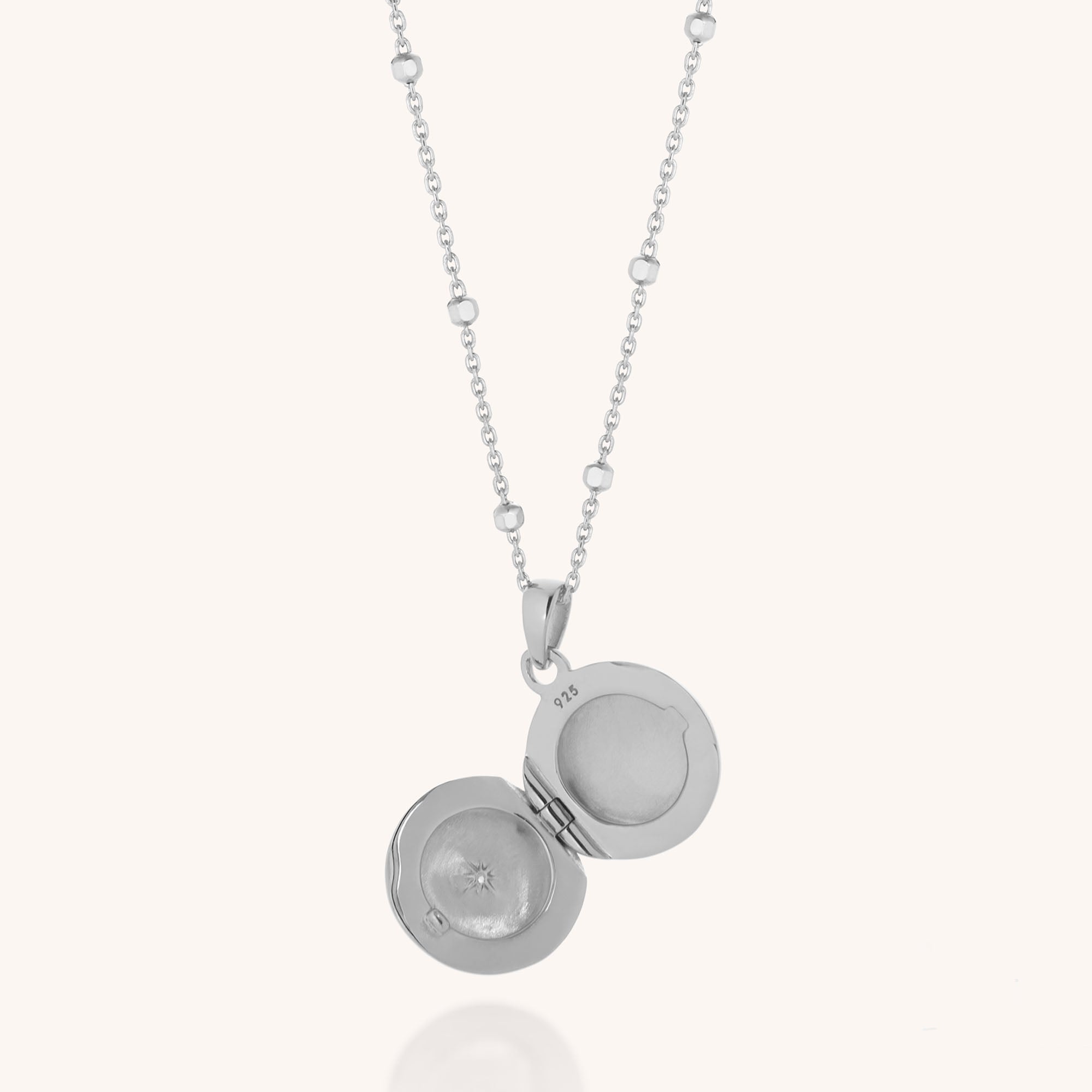 The Starlight Keepsake Locket Necklace features a sterling silver round open pendant on a delicate chain, ready to hold a cherished photo. Sparkling cubic zirconia accents complete its elegant look.