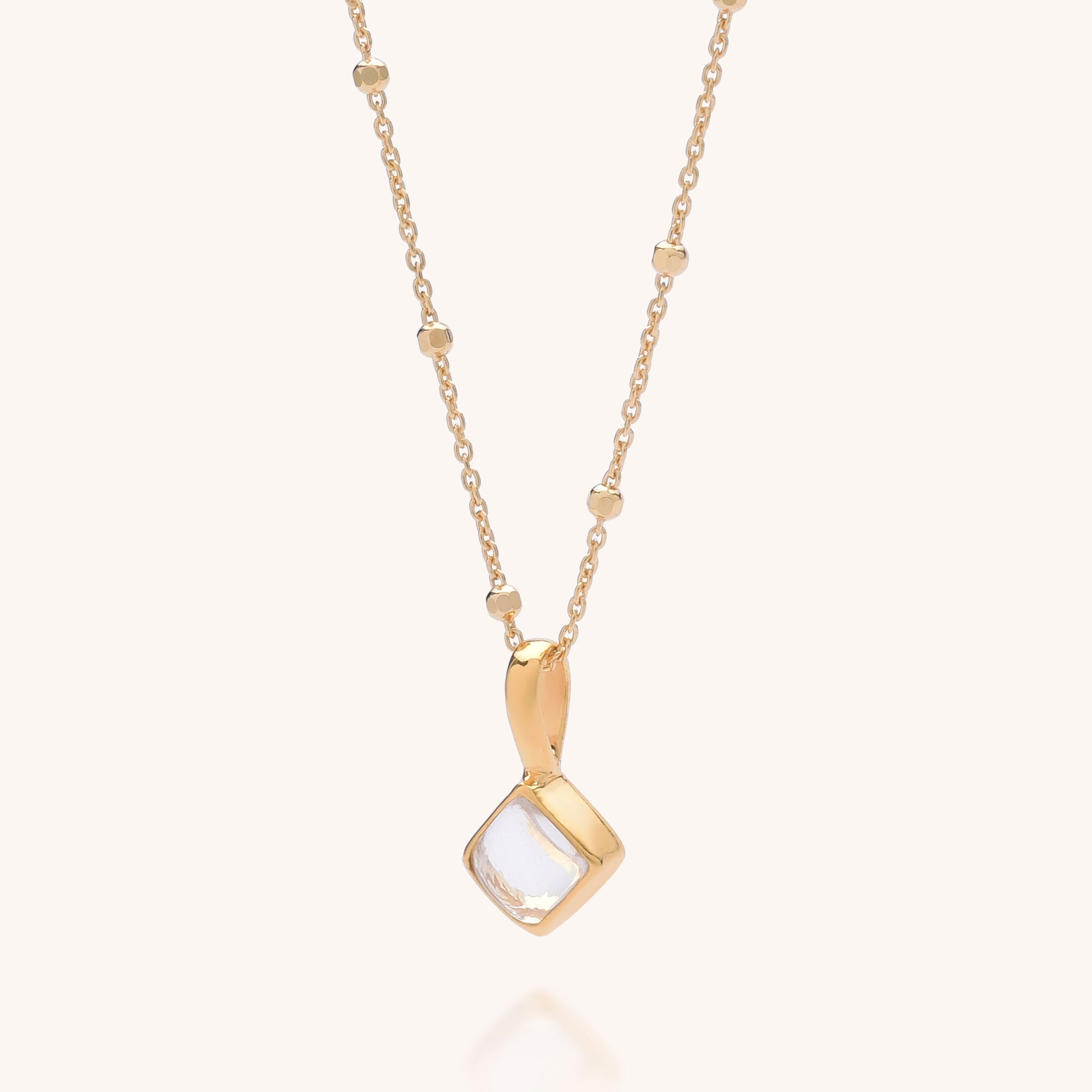 The Diamond April Birthstone Necklace features a delicate gold chain with small bead accents and a square-shaped natural crystal gemstone pendant set in a gold frame.