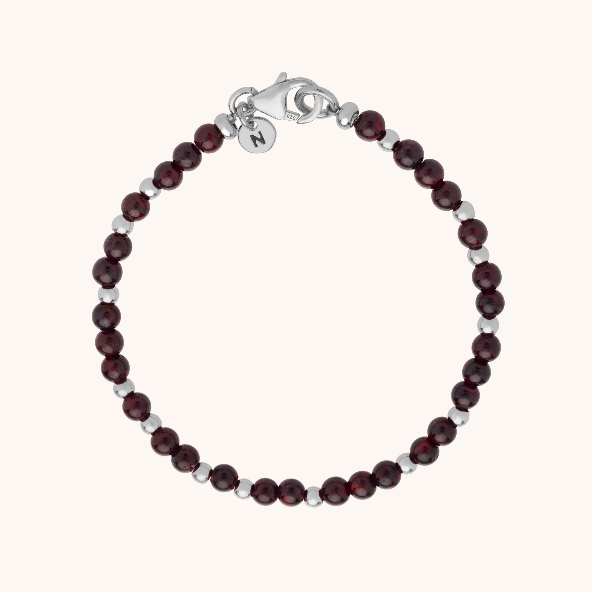 The Jewel Bead Bracelet showcases alternating dark red natural gemstones and eco-silver sterling silver beads, finished with a lobster clasp and round charm, elegantly displayed on a light background.