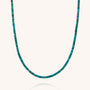 A close-up of the Turquoise Heishi Necklace, featuring eco-friendly, flat turquoise-colored beads arranged in a single strand against a light background.