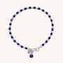 The Linear Birthstone Bracelet - September features alternating sterling silver and deep blue lapis lazuli beads, a lobster clasp, and two small silver charms—one engraved, the other adorned with a blue stone.