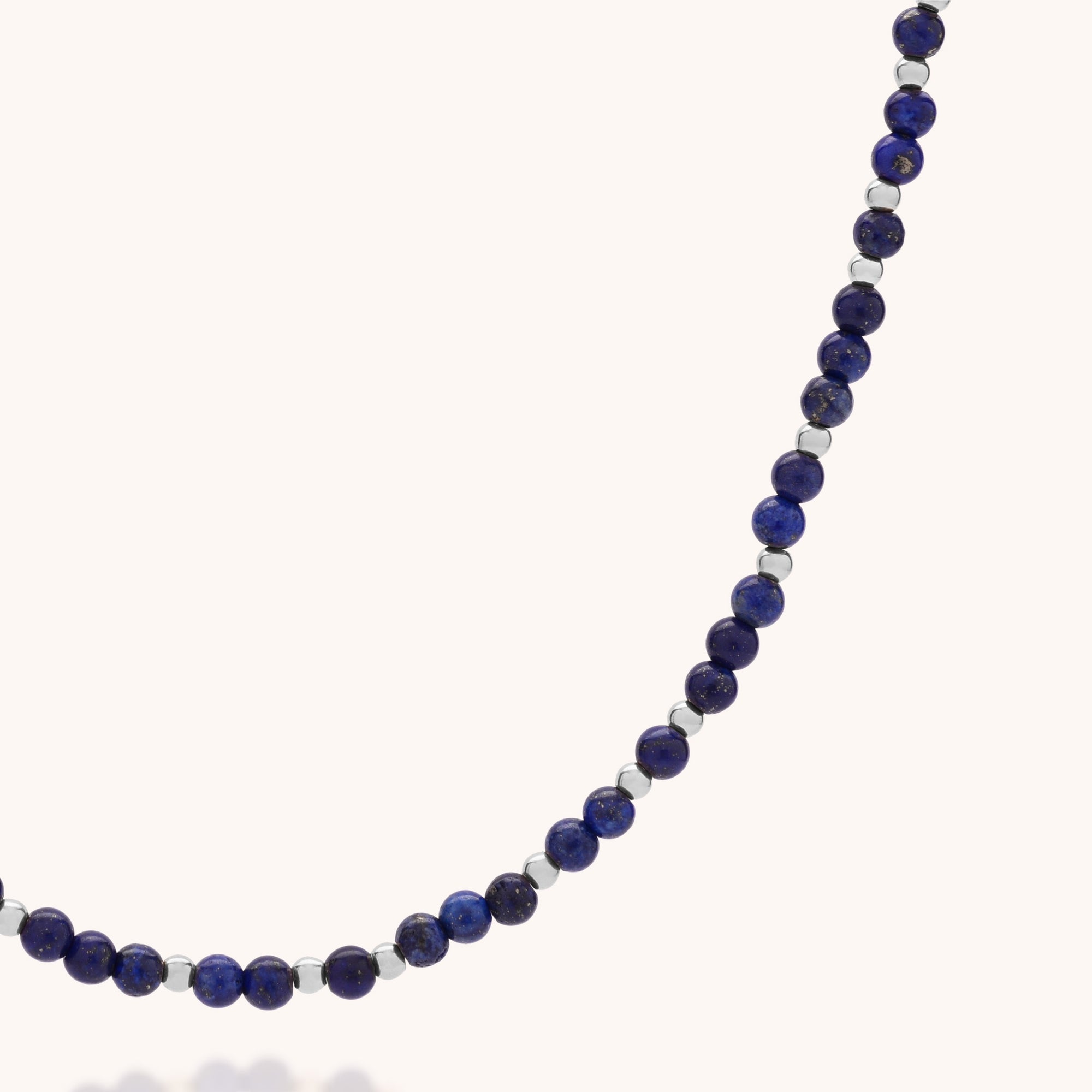 A close-up of the Jewel Bead Birthstone Necklace - September: a handcrafted UK piece with alternating dark blue lapis lazuli and silver round beads, displayed against a plain light background.