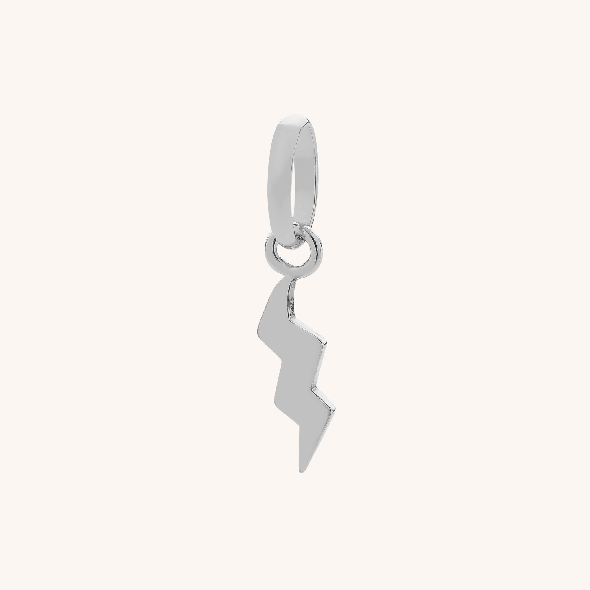 The Lightning Charm is a sterling silver lightning bolt hanging from a small circular loop, perfect for adding striking detail to your sterling silver jewelry collection.