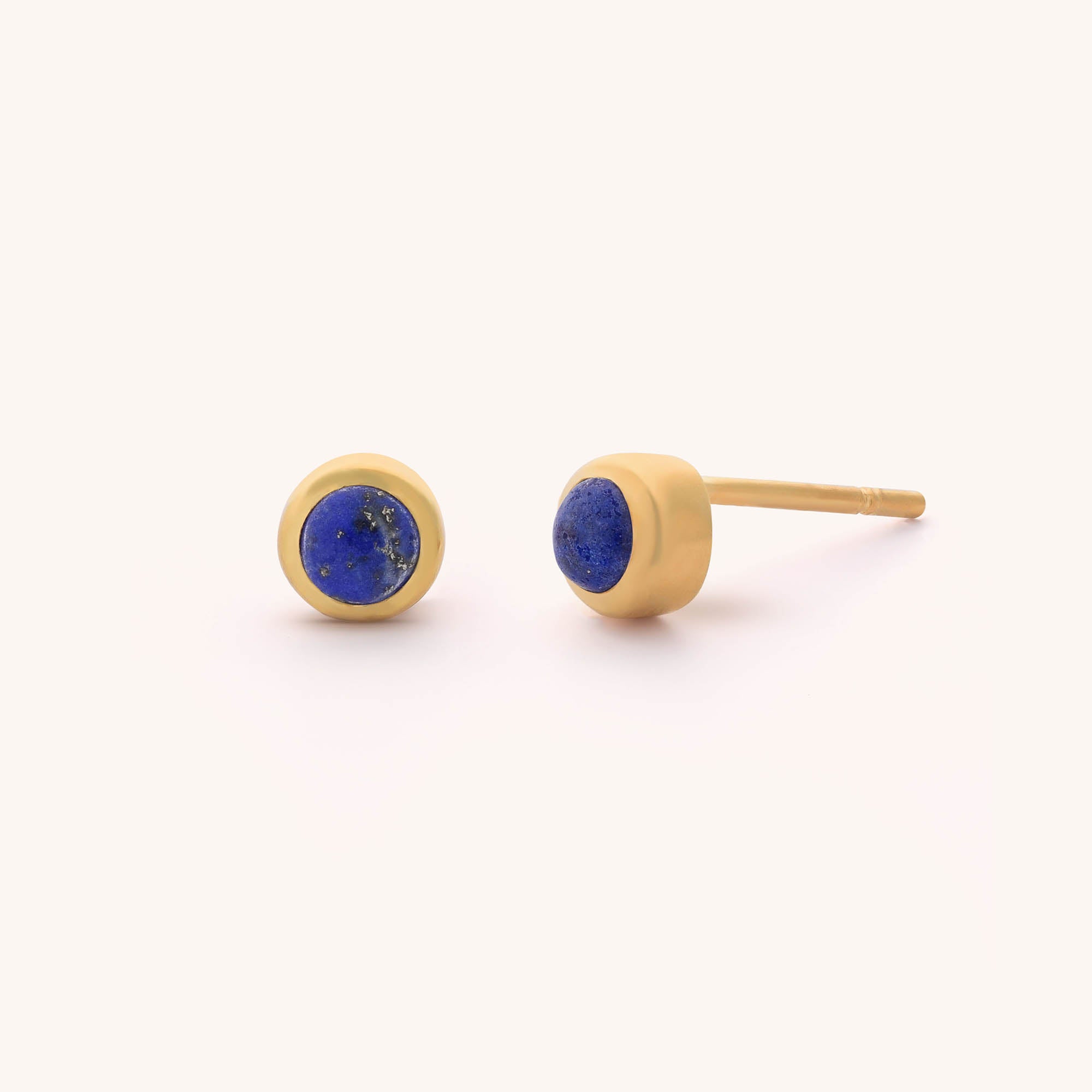 Mini Gem Dot Birthstone Earrings feature stunning round blue gemstones set against a plain light background, offering an elegant and charming classic design.