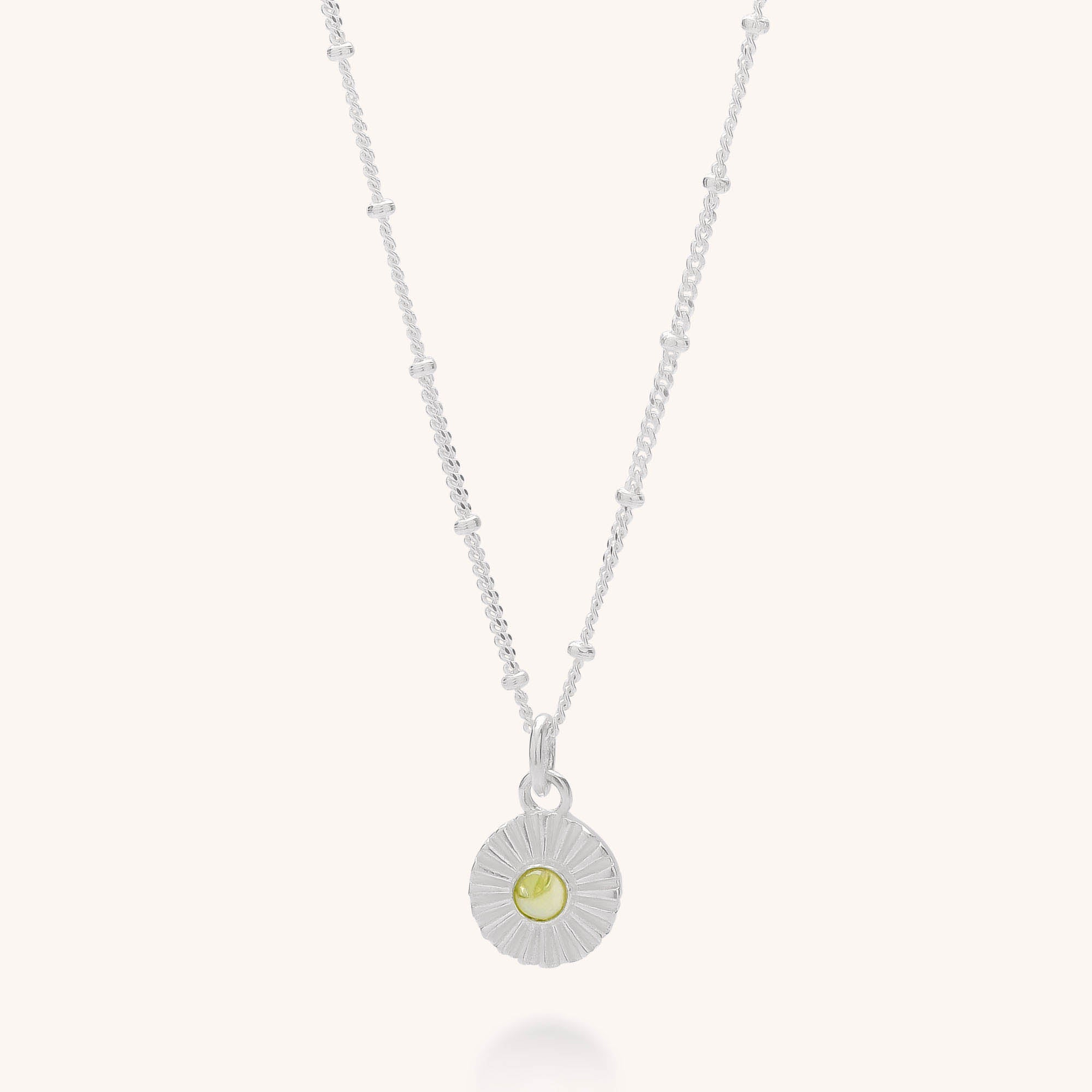 The Radiance Birthstone Necklace - August features a sterling silver pendant with a beaded chain and round sunburst design, highlighted by a peridot gemstone at the center—ideal for gifting in its included box.