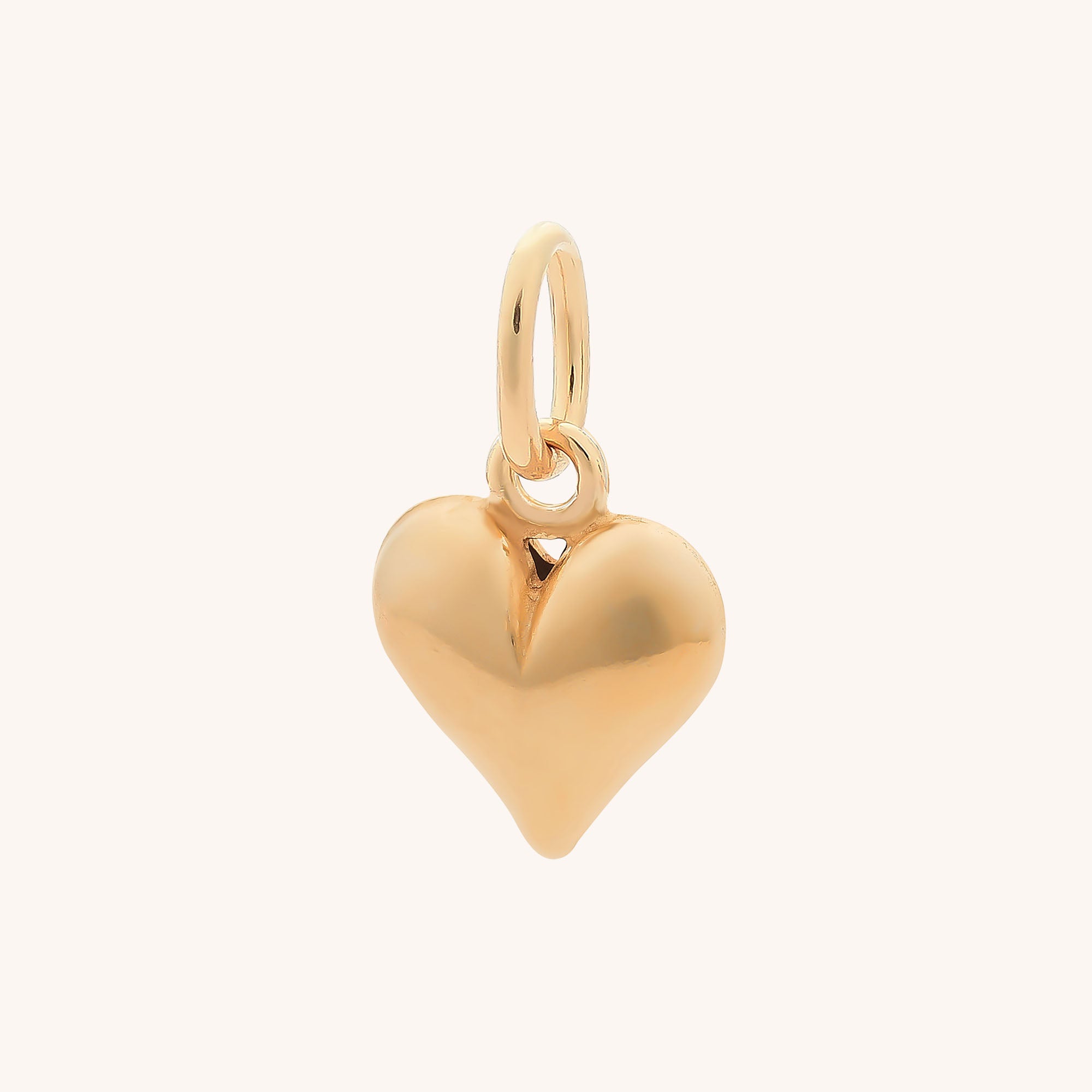 The Heart Charm is a shiny gold, heart-shaped pendant with a smooth surface and a small loop—ideal as a necklace charm or for pairing with sterling silver bracelet charms, shown against a light background.