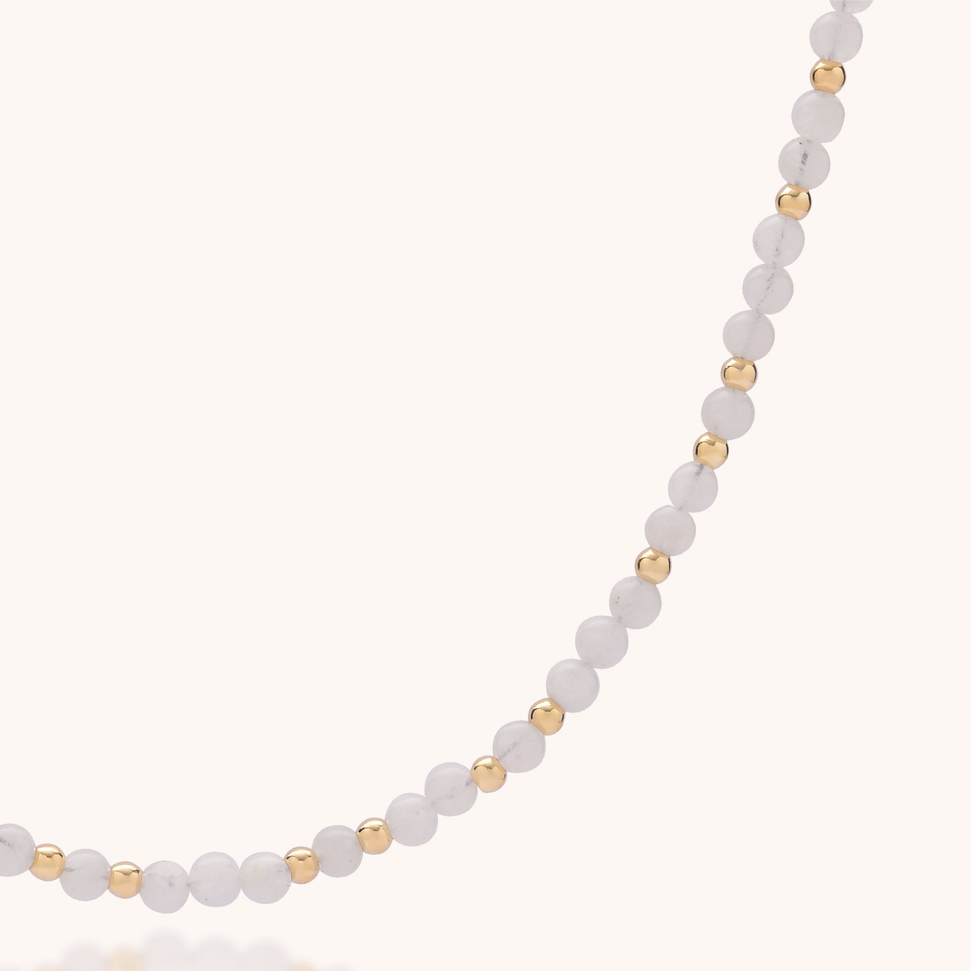 Close-up of the Jewel Bead Birthstone Necklace - June, showcasing alternating white and gold beads, accented with a Rainbow Moonstone—the June birthstone—against a plain light background.