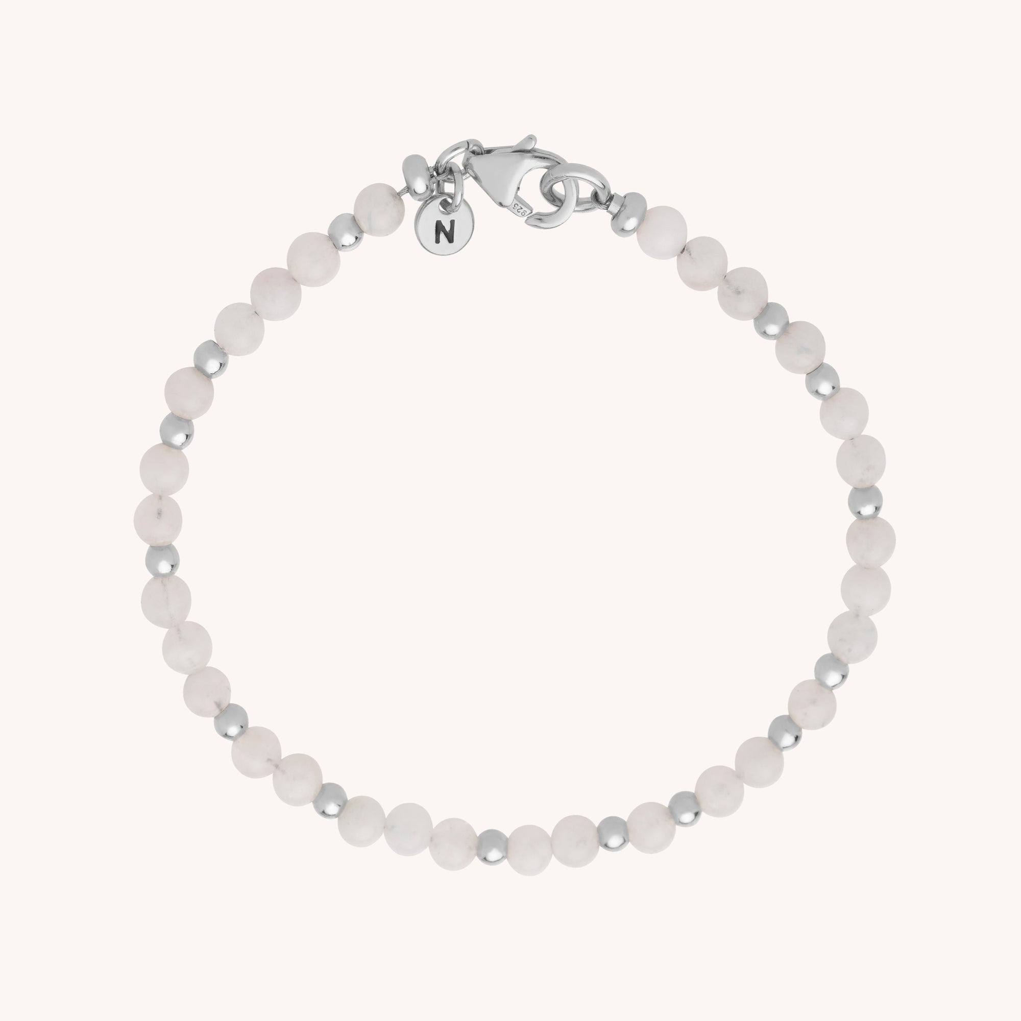 The Jewel Bead Bracelet features alternating small white and eco-silver sterling silver beads, finished with a silver clasp and a circular charm engraved with the letter N.
