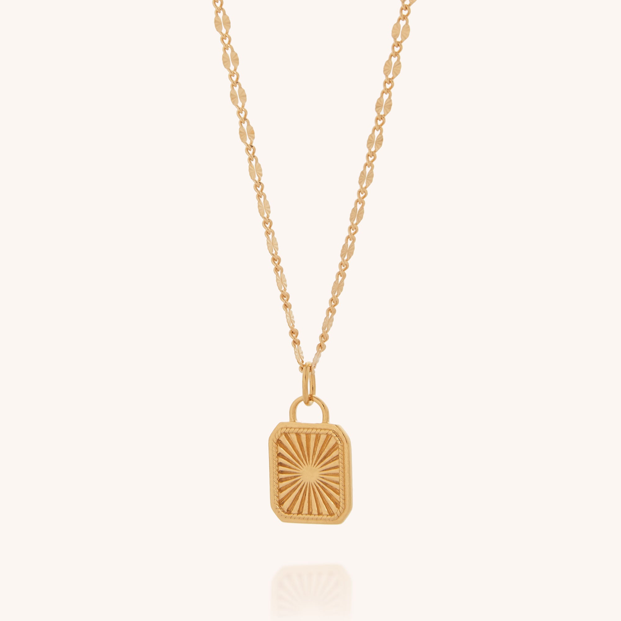 The Golden Dawn Necklace is a gold chain with a rectangular sunburst pendant, shown against a plain light background.